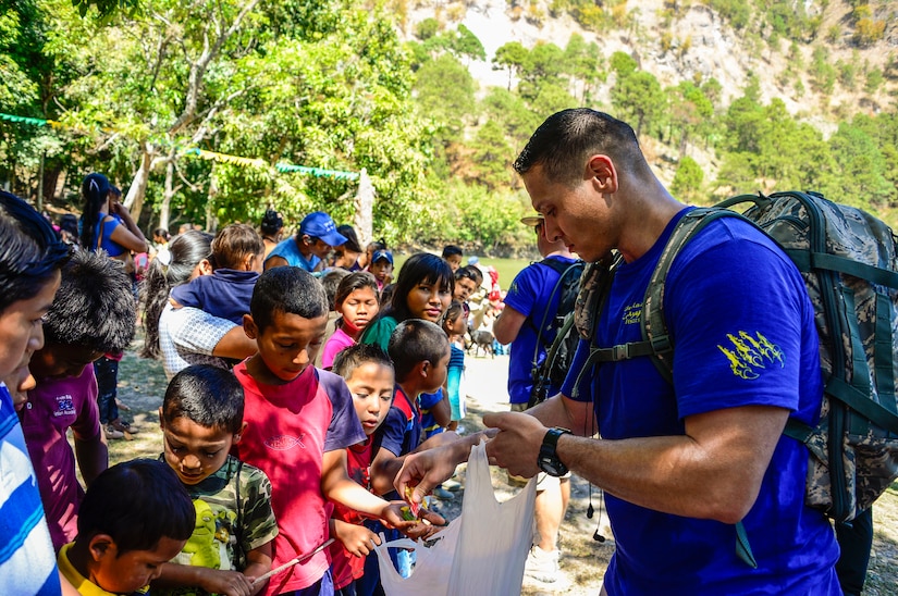 U.S. Air Force Staff Sgt. Christopher Srock, Joint Task Force-Bravo Command Judge Advocate noncommissioned officer in charge, passes candy to children from Laguna, Honduras, Feb. 28, 2015. As part of the 59th Chapel Hike, more than 172 members assigned to Joint Task Force-Bravo laced up their hiking boots and completed a seven-mile round trip hike to deliver over 4,500-pounds of donated try goods to villagers in need. (U.S. Air Force photo/Tech. Sgt. Heather Redman) 