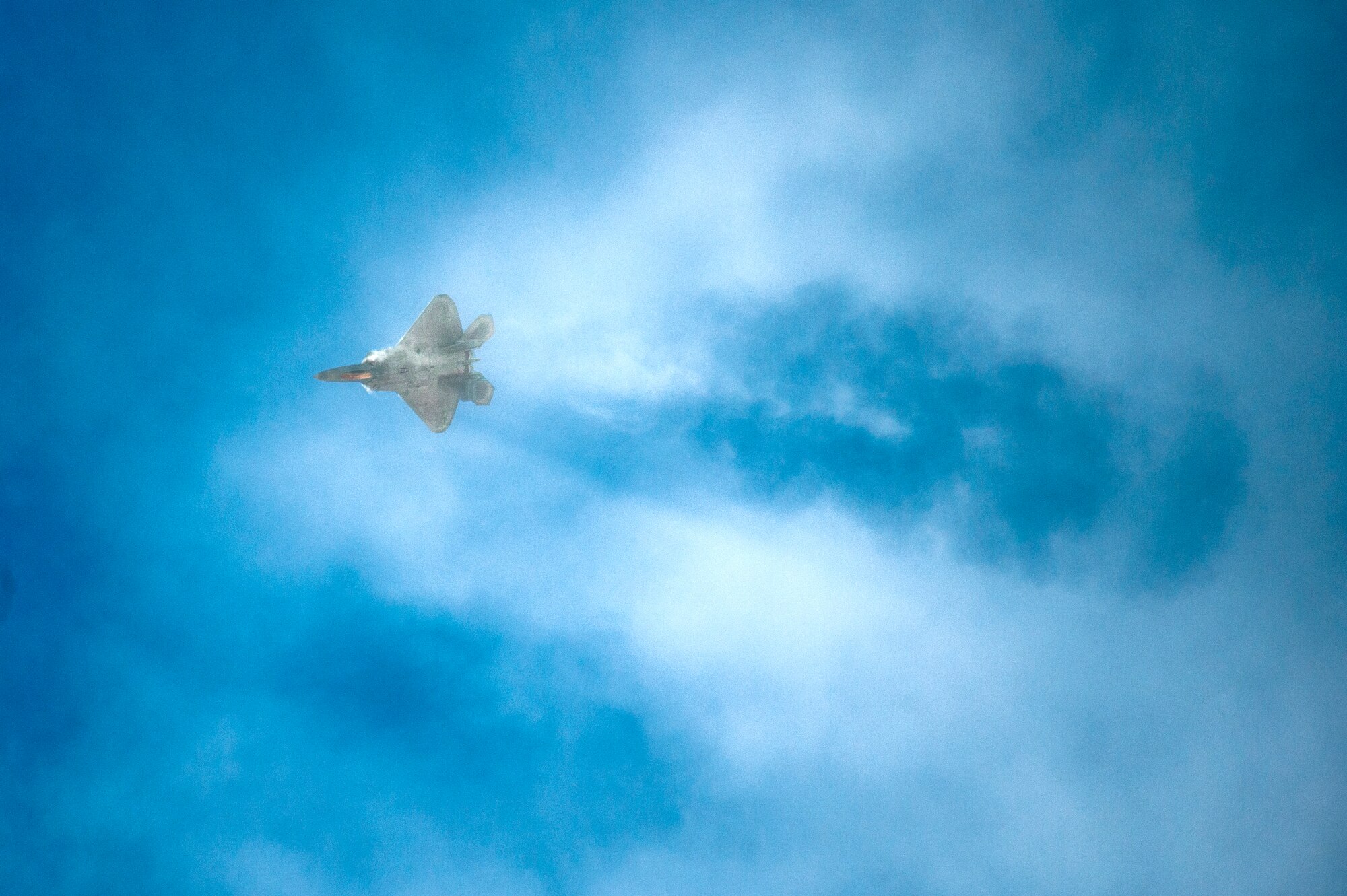 An F-22 Raptor cuts through the clouds during the 2015 Heritage Flight Training and Certification Course at Davis-Monthan Air Force Base, Ariz., March 1, 2015.  The annual aerial demonstration training event has been held at D-M since 2001, providing civilian and military pilots the opportunity to practice flying in formation for the upcoming air show season. (U.S. Air Force photo by Airman 1st Class Chris Massey/Released)