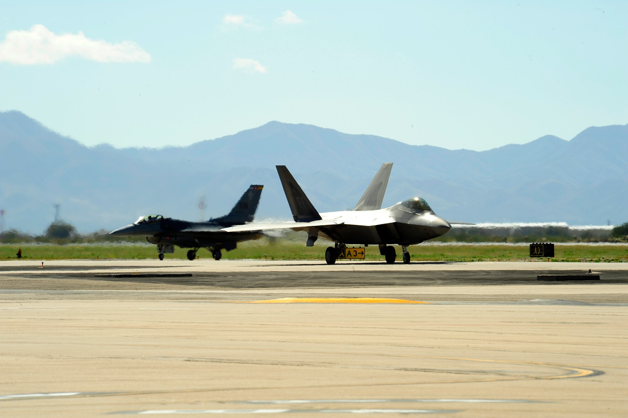 A F-22 Raptor and a F-16 Fighting Falcon taxi back to their parking spot after practicing an aerial demonstration during the 2015 Heritage Flight Training and Certification Course at Davis-Monthan Air Force Base, Ariz., March 1, 2015. The annual aerial demonstration training event has been held at D-M since 2001, providing civilian and military pilots the opportunity to practice flying in formation for the upcoming air show season. (U.S. Air Force photo by Tech. Sgt. Courtney Richardson/Released)