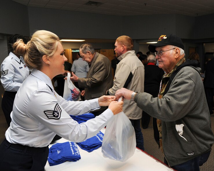 Staff Sgt. April Breithaupt, 2nd Aerospace Medical Squadron, medical admission technician, hands out gift bags to World War II veterans during the WWII luncheon on Barksdale Air Force Base, La., Feb. 27, 2015. The gifts included a specially designed shirt, hat and coin to show appreciation to the veterans. (U.S. Air Force photo/ Senior Airman Jannelle Dickey)