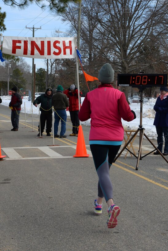 A runner reaches the finish line during the 17th Annual Fort Eustis 10K Run at Fort Eustis, Va., Feb. 28, 2015. Runners wore several layers of clothing to endure the 28-degree weather as they ran through Fort Eustis. (U.S. Air Force photo by Staff Sgt. Teresa J. Cleveland/Released)