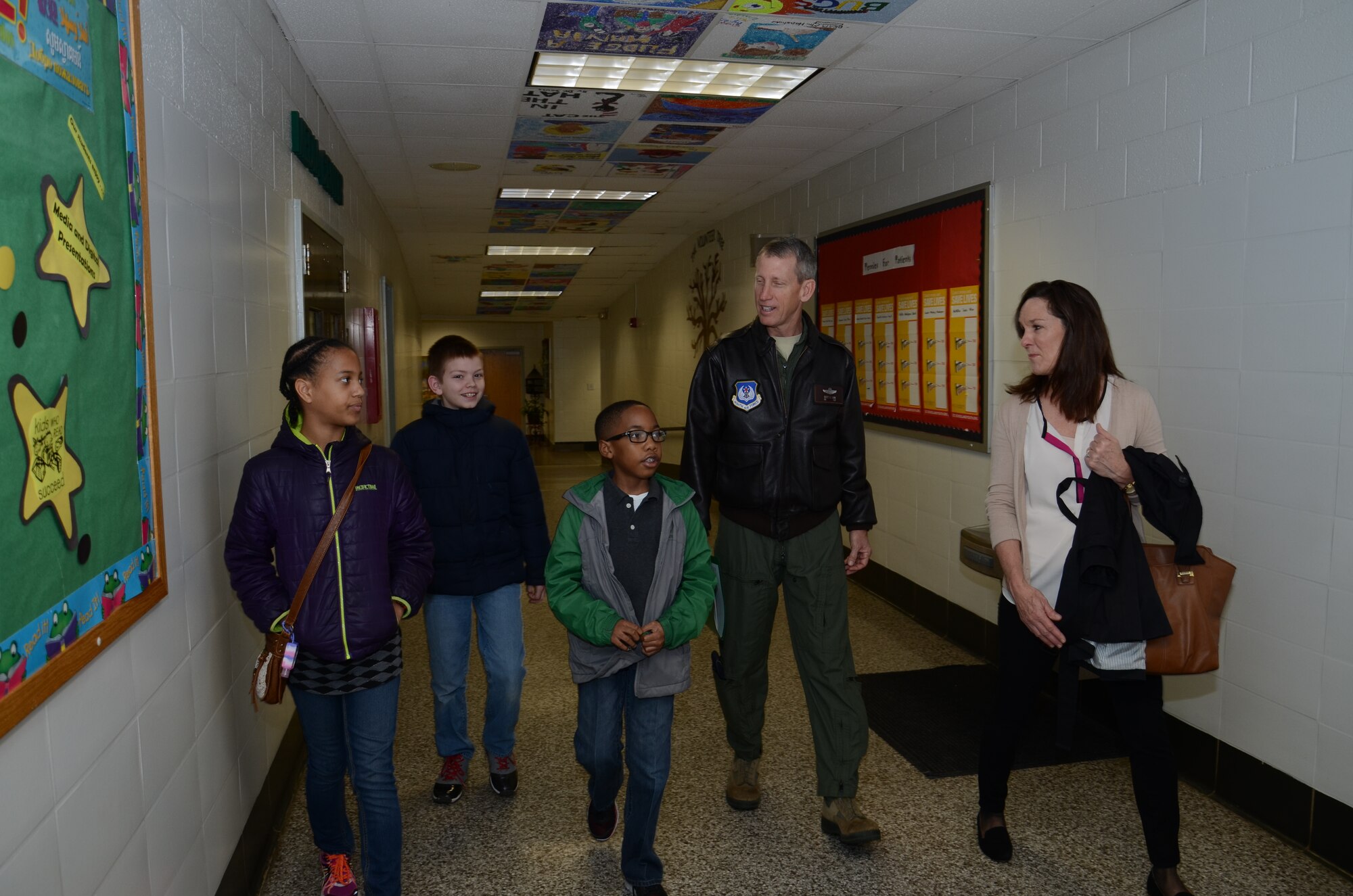 U.S. Air Force Col. Scott Caine, Ninth Air Force vice commander, and his wife, Pam, are escorted by members of the Welcome Committee at High Hills Elementary School, Shaw Air Force Base, S.C., March 2, 2015. The students escorted the Caines to the multipurpose room and gave them a tour of the school during their visit on Read Across America Day. [Left to right] Eden, Tyler, and Joshua are fifth-grade students at High Hills Elementary School. (U.S. Air Force photo by Master Sgt. Latisha Cole/Released)