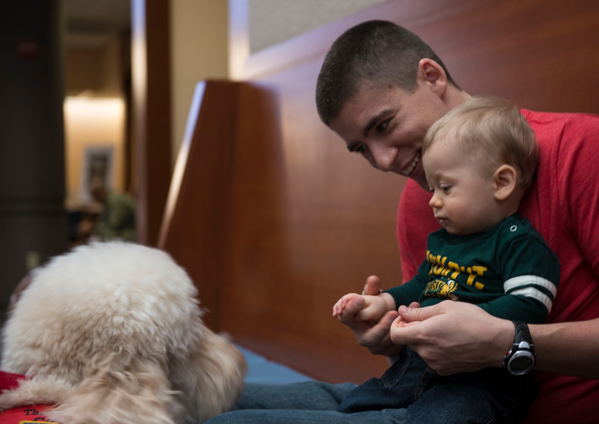Callie, a Furry Angels therapy dog, approaches a young boy and his father at the clinic on Joint Base McGuire-Dix-Lakehurst, N.J. Feb. 26, 2015. The Furry Angels are volunteer dog and handler teams that provide therapy to sick or injured people. (U.S. Air Force photo by Airman 1st Class Joshua D. King/ Released)