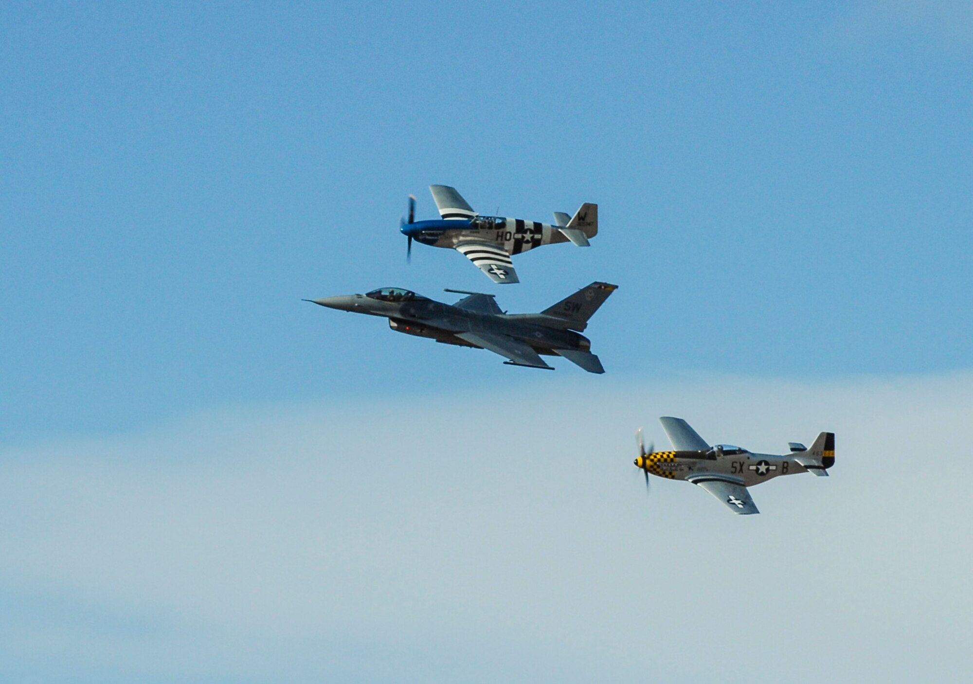 Two P-51 Mustangs fly beside an F-16 Fighting Falcon during the Heritage Flight Training and Certification Course at Davis-Monthan Air Force Base, Ariz., Feb. 28, 2015. The annual aerial demonstration training event has been held at D-M since 2001, providing civilian and military pilots the opportunity to practice flying in formation for the upcoming air show season. (U.S. Air Force photo by Airman 1st Class Cheyenne Morigeau/Released) 
