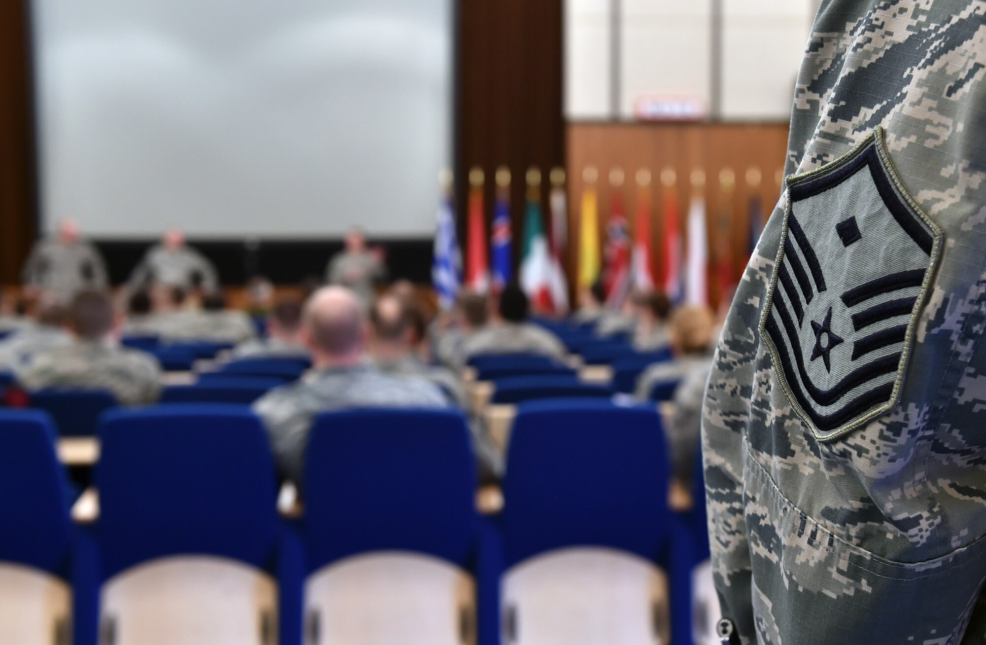 A first sergeant watches from the back of the auditorium during the Kaiserslautern Military Community First Sergeant Council's First Sergeant Symposium at Einsiedlerhof, Germany, Feb. 26, 2015. A group of enlisted leaders including the chief master sergeant of the Romanian, Slovak and Estonian air forces and other leaders from the German, Italian, Slovenian and the United Kingdom’s air forces visited Ramstein before attending the First Sergeant Symposium. More than 120 students attended the annual symposium. (U.S. Air Force photo/Staff Sgt. Sara Keller)