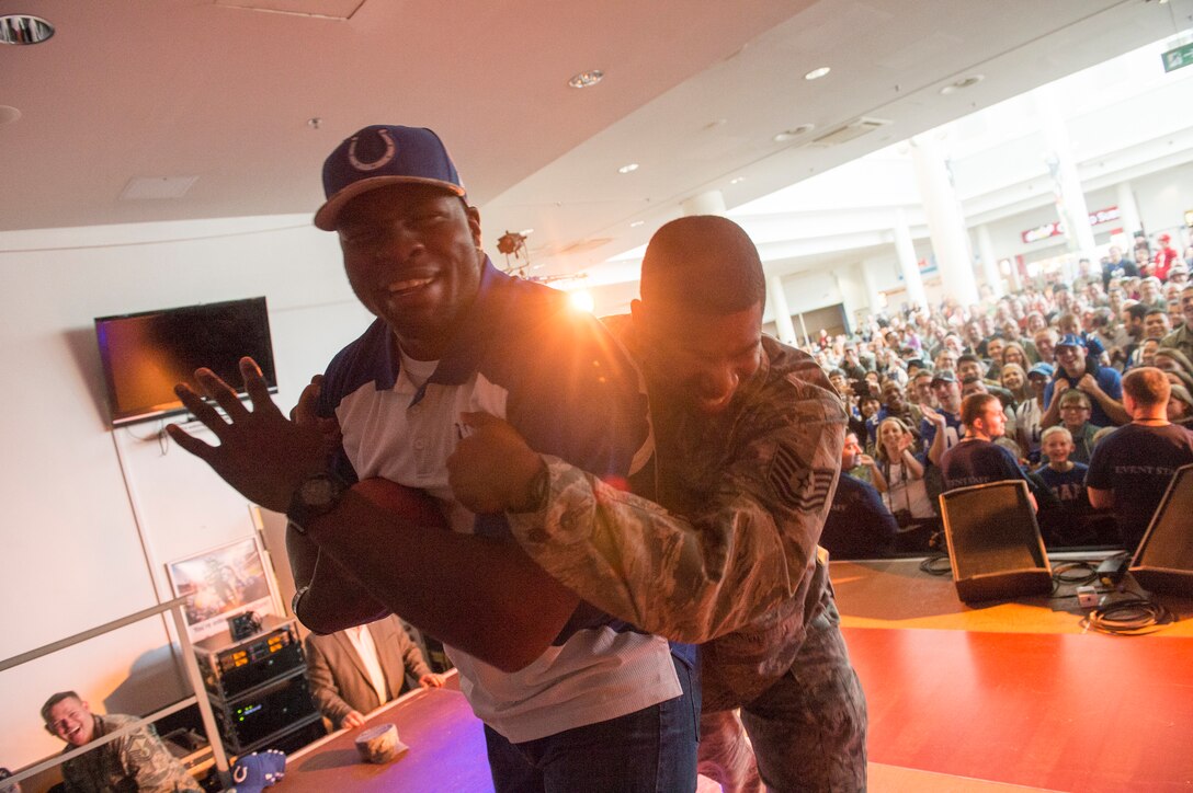 A U.S. airman tackles Indianapolis Colts tight end Dwayne Allen on stage at a USO show on Ramstein Air Base in Germany, March 3, 2015.