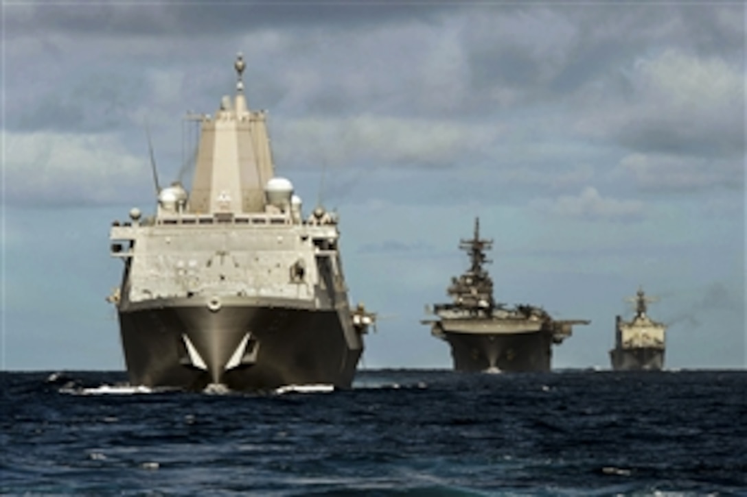 The transport dock ship USS Anchorage, left, the amphibious assault ship USS Essex, center, and the amphibious landing dock ship USS Rushmore participate in a simulated strait transit in the Pacific Ocean, Feb. 28, 2015.

