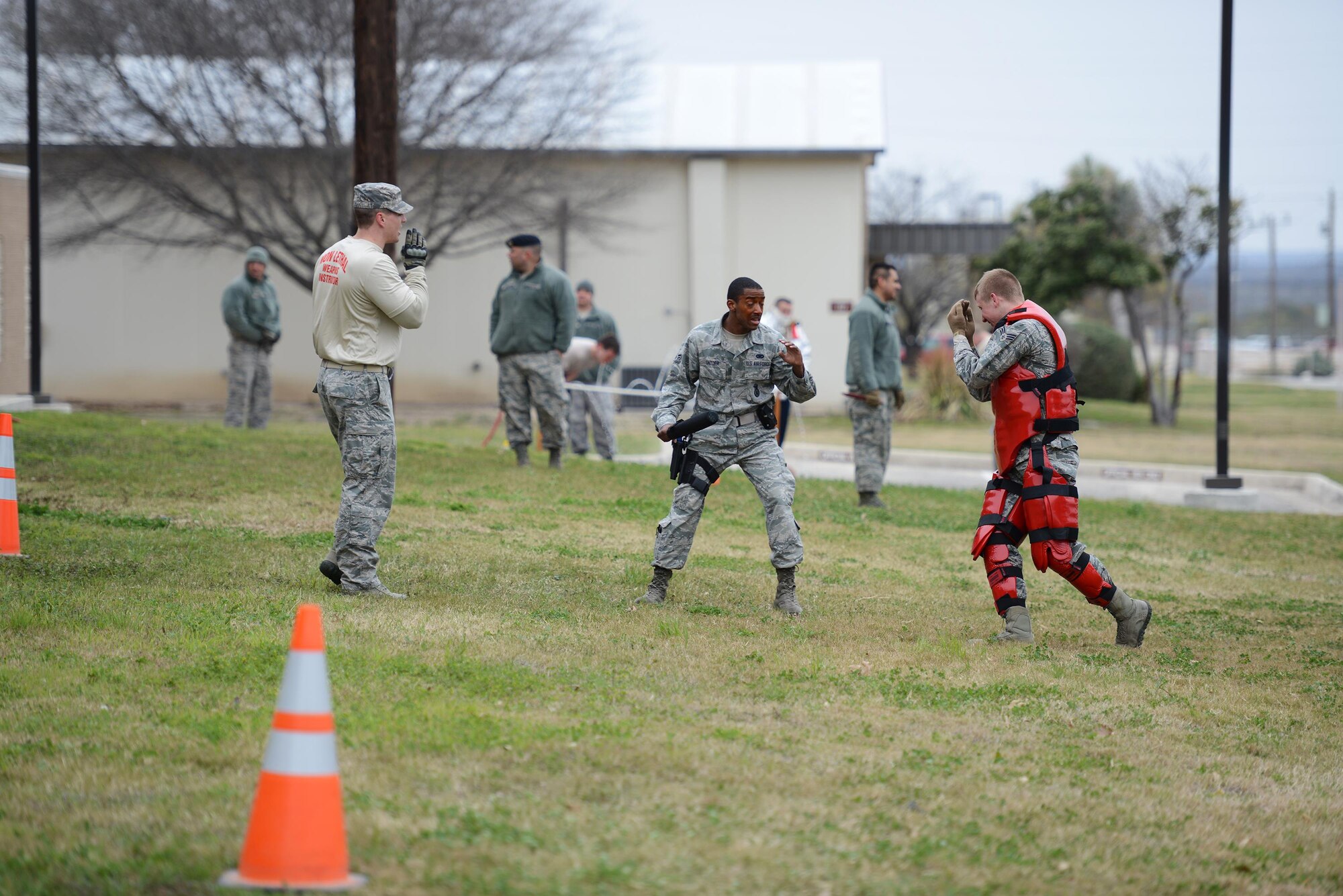 Airman 1st Class Jalen Snyder, center, 47th Security Forces Squadron patrolman, fends off Senior Airman Jacob Eckert, 47th SFS patrolman, in the RedMan suit after a level one contamination of oleoresin capsicum on Laughlin Air Force Base, Texas, Feb. 27, 2015. The RedMan suit is a form-fitted exoskeleton made of closed cell foam with a slick finish and is designed to protect the wearer from blunt trauma when training. Realistic training that places law enforcement officers into situations that simulate the stress and risk of the job, but that also avoids training injuries, is optimal. (U.S. Air Force photo by Tech. Sgt. Steven R. Doty)