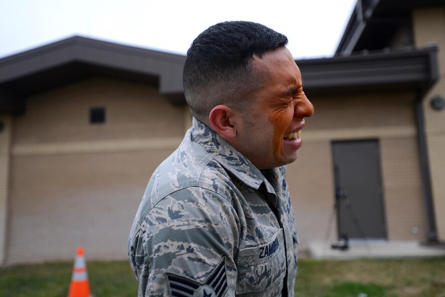 U.S. Air Force reservist Staff Sgt. Hector Ramora, temporarily assigned to the 47th Security Forces Squadron, winces in pain from a level one contamination of oleoresin capsicum on Laughlin Air Force Base, Texas, Feb. 27, 2015. OC is a natural oil found in many types of hot peppers, including cayenne peppers and other chili peppers, and when sprayed into the face of an attacker is extremely irritating to the skin, eyes, mouth, throat and lungs. Its effect is immediate and powerful, helping to distract a person long enough to escape an assailant or for a police officer to take control of a subject. (U.S. Air Force photo by Tech. Sgt. Steven R. Doty)