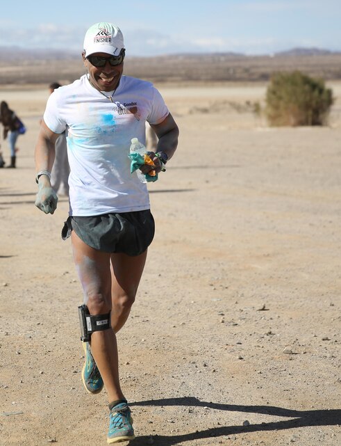 First Sgt. Jairo Fredonis, Weapons Company, 1 Battalion 7th Marine Regiment, crosses the finish line of Condor Elementary School’s first 5 kilometer Color Run at the Combat Center’s Physical Fitness Test track, Feb. 28, 2015. The event was equipped with color stations along the course, giving water to runners and tossing colored cornstarch as they ran by. (Official Marine Corps photo by Lance Cpl. Thomas Mudd/ Released)