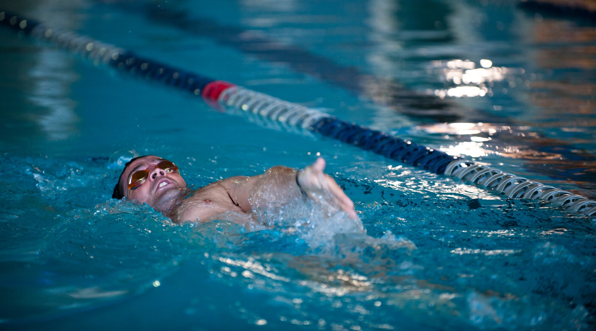 Tech. Sgt. Dave Scarborough, 58th Rescue Squadron survival evasion resistance and escape specialist, demonstrates proper backstroke form while volunteering at a 2015 U.S. Air Force Trials practice swim session at Nellis Air Force Base, Nev., Feb. 27, 2015. Adaptive athletic reconditioning is proven to have positive lasting effects on recovering service members’ physical and emotional well-being. By supporting the trials, the Air Force is demonstrating its commitment to wounded warriors and their families. (U.S. Air Force photo by Senior Airman Thomas Spangler)