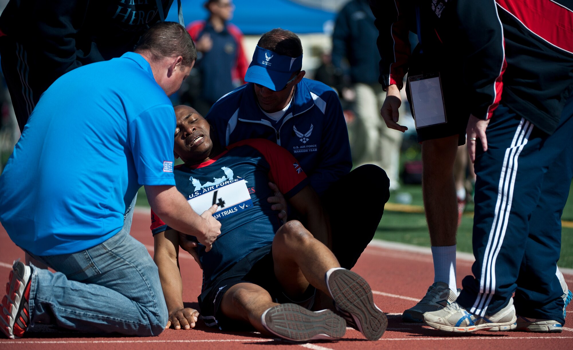 A member of the 2015 U.S. Air Force Trials British track team is consulted by members of the Air Force Trials staff after falling at the end of a 100-meter race at Nellis Air Force Base, Nev., March 3, 2015. More than 200 members of Nellis and Creech AFBs volunteered to help out during the trials, which will run Feb. 27 to March 5. (U.S. Air Force photo by Staff Sgt. Siuta B. Ika)