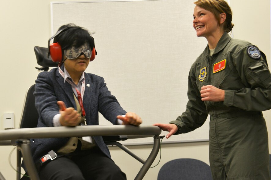 Staff Sgt. Bethany Whiteley, 92nd Aerospace Medical Squadron aerospace physiology craftsman demonstrates the Barany chair with a Japanese instructor from Iwate Prefectural University in Morioka, Japan during a base tour March 3, 2015, at Fairchild Air Force Base, Wash. The Barany chair is a training tool that helps Airmen understand spatial disorientation and learn to trust the instruments. (U.S. Air Force photo/Senior Airman Janelle Patiño)