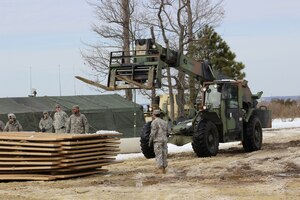 U.S. Army Soldiers from the 331st Transportation Company (Causeway), 11th Transportation Battalion, 7th Transportation Brigade (Expeditionary), lay down tiles on the muddy ground around the area of operations during a Logistics Over the Shore exercise at Fort Eustis Va., Feb. 28, 2015. The exercise simulates transporting vehicles and equipment onto a bare beach. (U.S. Army photo by Spc. Aaron Campbell/Released)