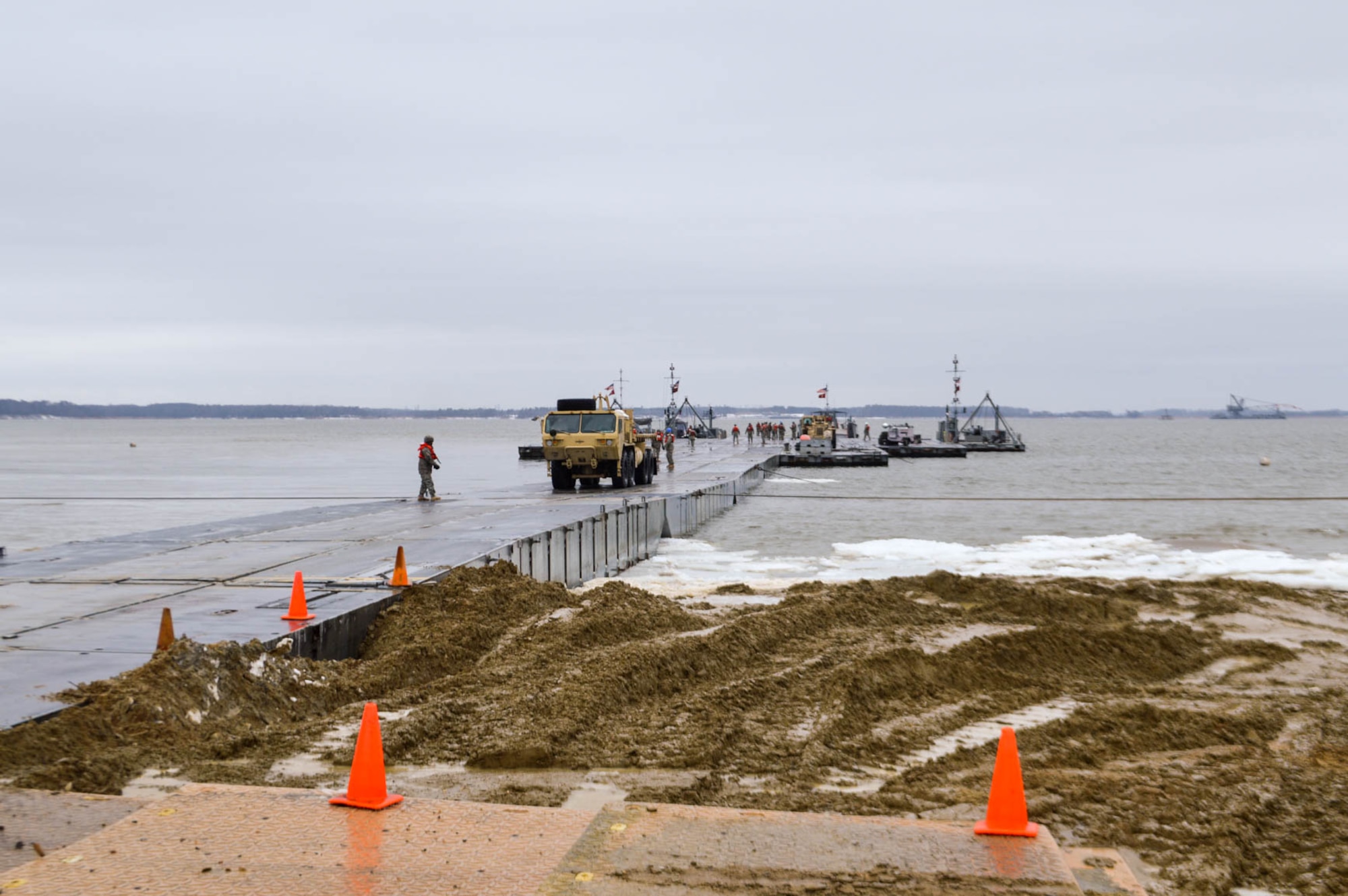 U.S. Army Soldiers from the 7th Transportation Brigade (Expeditionary) drive equipment over a modular causeway during a Logistics Over The Shore exercise at Fort Eustis, Va., March 1, 2015.  The LOTS event is used to demonstrate the Army’s premiere capability by establishing and managing port terminal operations and cargo by receiving large cargo vessels and transferring supplies to port using the Army’s Modular Causeway System. (U.S. Army photo by Spc. Marian Alleva/Released)
