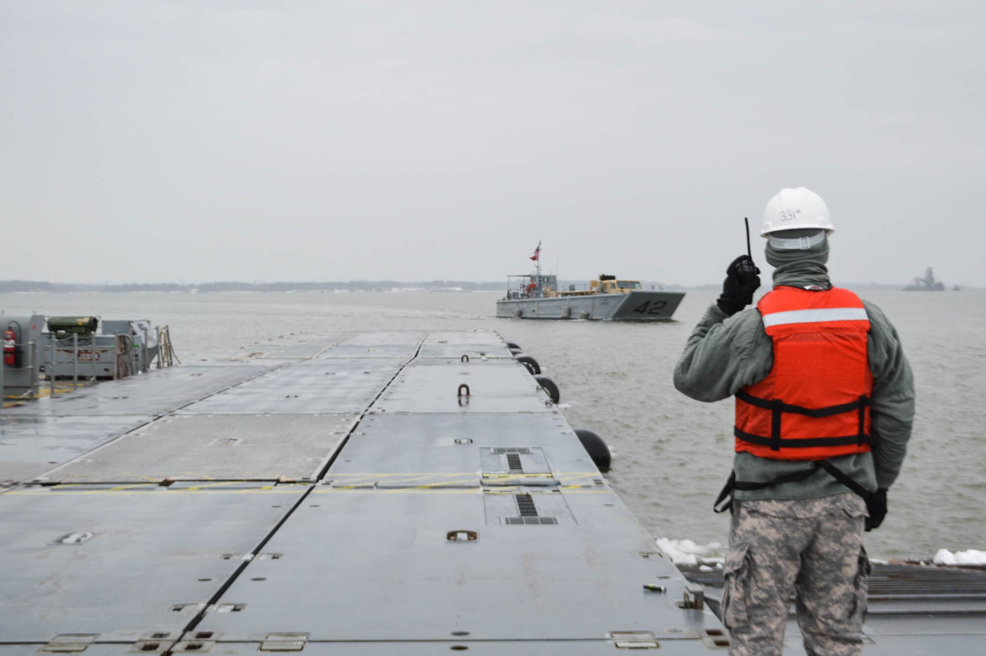 A U.S. Army Soldier from the 331st Transportation Company (Causeway), 11th Transportation Battalion, 7th Transportation Brigade (Expeditionary) watches as a Landing Craft Mechanized LCM-42 boat prepares to approach the Trident Pier to off-load cargo at Fort Eustis, Va., March 1, 2015. The 7th Trans. Bde. (Ex.) conducted a bare beach Logistics Over The Shore operation to train for an upcoming mission.  (U.S. Army photo by Spc. Marian Alleva/Released)