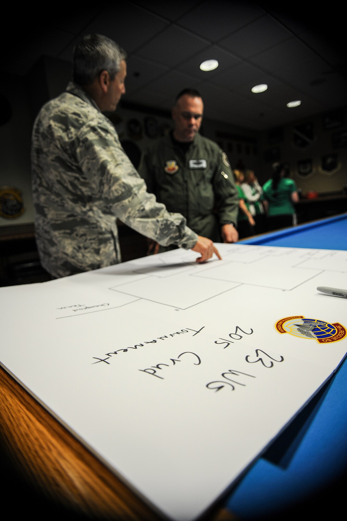 U.S. Air Force Maj. Joe Barnard, left, 38th Rescue Squadron commander, explains the brackets to the crudmaster, Col. Eric Trychon, 93d Air Ground Operations Wing vice commander, before the Moody Air Force Base Annual Wives Crud Tournament Feb. 27, 2015 at Moody AFB, Ga. The crudmaster is the tournament referee and is positioned at the center of one of the table’s long sides. (U.S. Air Force photo by Andrea Jenkins/Released)

