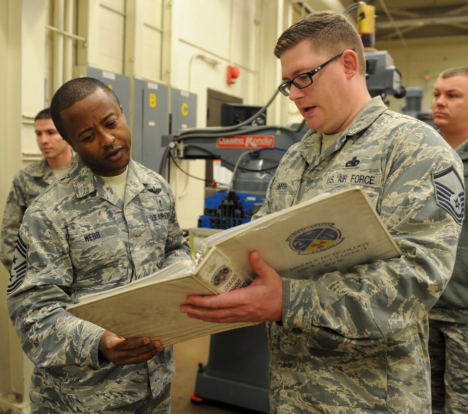 U.S. Air Force Chief Master Sgt. 	Eddie Webb, 7th Bomb Wing command chief, reads through a binder containing safety Air Force Instructions with Master Sgt. Marshall Smith, 7th Equipment Maintenance Squadron aircraft metals technology section chief, Nov. 25, 2014, at Dyess Air Force Base, Texas.  Webb accompanied the 7th Bomb Wing safety office to the metals technology shop as part of Webb’s program, “Teach the Chief.” This program gives Webb the opportunity to spend a day performing the duties of enlisted Airmen from a different career field each month. (U.S. Air Force photo by Airman 1st Class Autumn Velez/Released)