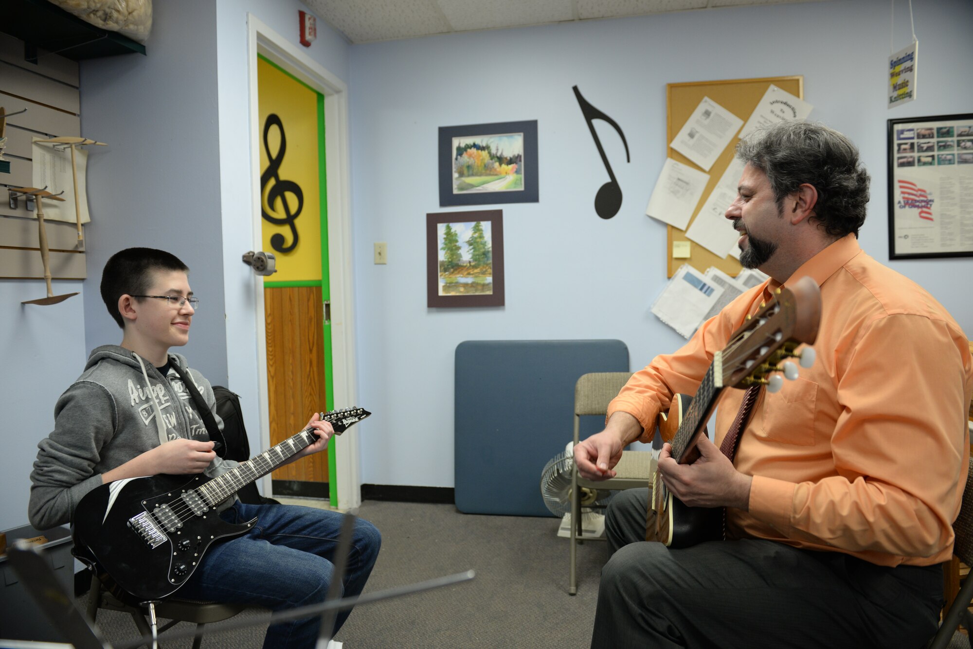 Roger Drinnon, Air Mobility Command’s Deputy Chief of Current Operations, teaches one of his students how to play a particular part of a song at the Scott Air Force Base Arts and Crafts Center, Jan. 20, 2015. Drinnon considers practice and repetition as the only way to improve any skill, such as playing guitar. (U.S. Air Force photo by Airman 1st Class Erica Crossen)
