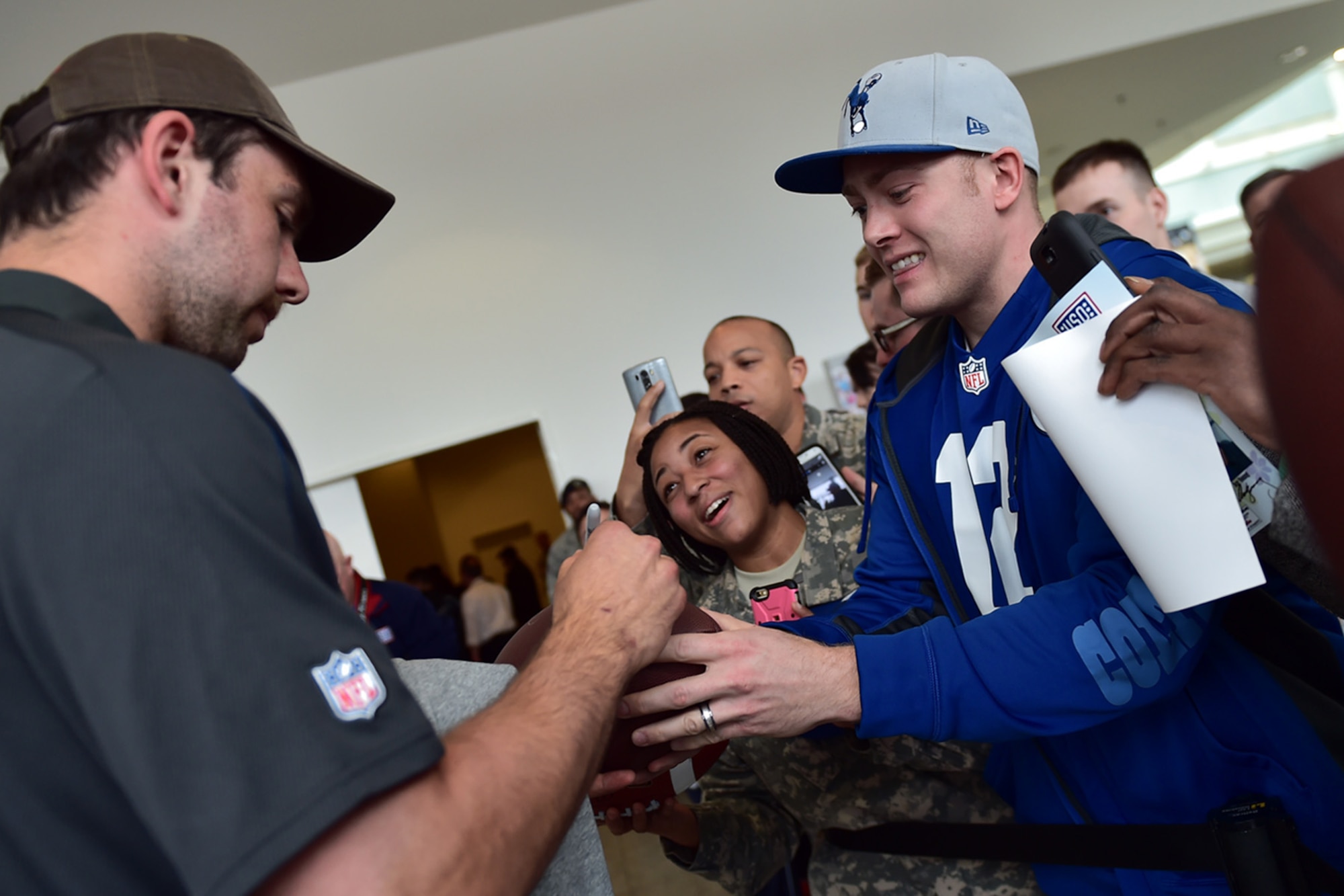 Andrew Luck, Indianapolis Colts quarterback, signs a football for a fan during the USO Spring Visit at Ramstein Air Base, Germany, March 3, 2015. For their first stop of a multi-country tour, the USO brought Indianapolis Colts players Andrew Luck and Dwayne Allen, Colts coach Chuck Pagano, Pittsburgh Steelers player David DeCastro, entertainers Philip Phillips, Dennis Haysbert, Miss America 2015, Ace Young, Diana DeGarmo, and Jason “Wee Man” Acuna to Ramstein to visit military members and their families. (U.S. Air Force photo/Staff Sgt. Sara Keller) 