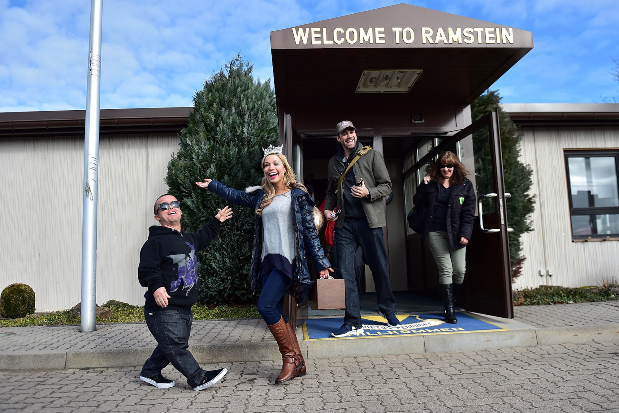 Kira Kazantsev, Miss America 2015, and Jason “Wee Man” Acuna, motion picture and television personality, exit the distinguished visitors lounge on her way to meet military members at the Kaiserslautern Military Community Center on Ramstein Air Base, Germany, March 3, 2015. For their first stop of a multi-country tour, the USO brought Indianapolis Colts players Andrew Luck and Dwayne Allen, Colts coach Chuck Pagano, Pittsburgh Steelers player David DeCastro, entertainers Philip Phillips, Dennis Haysbert, Miss America 2015, Ace Young, Diana DeGarmo, and Jason “Wee Man” Acuna to Ramstein to visit military members and their families. (U.S. Air Force photo/Staff Sgt. Sara Keller) 