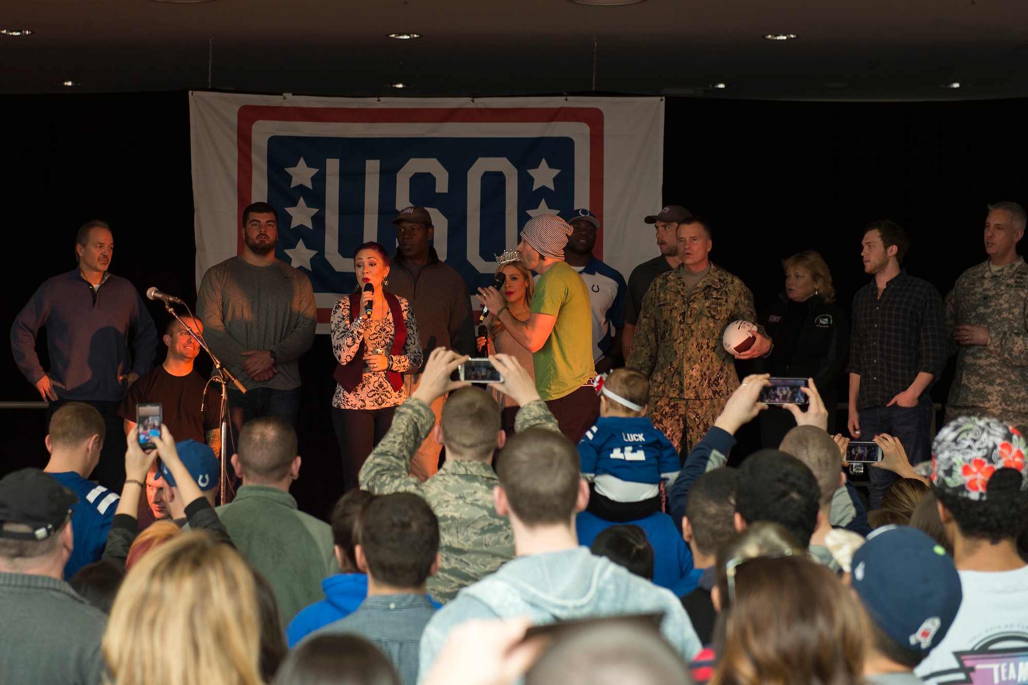 Celebrities sing for service members during the USO Spring Visit at Ramstein Air Base, Germany, March 3, 2015. For their first stop of a multi-country tour, the USO brought Indianapolis Colts players Andrew Luck and Dwayne Allen, Colts coach Chuck Pagano, Pittsburgh Steelers player David DeCastro, entertainers Philip Phillips, Dennis Haysbert, Miss America 2015, Ace Young, Diana DeGarmo, and Jason “Wee Man” Acuna to Ramstein to visit military members and their families. (U.S. Air Force photo/Senior Airman Damon Kasberg) 