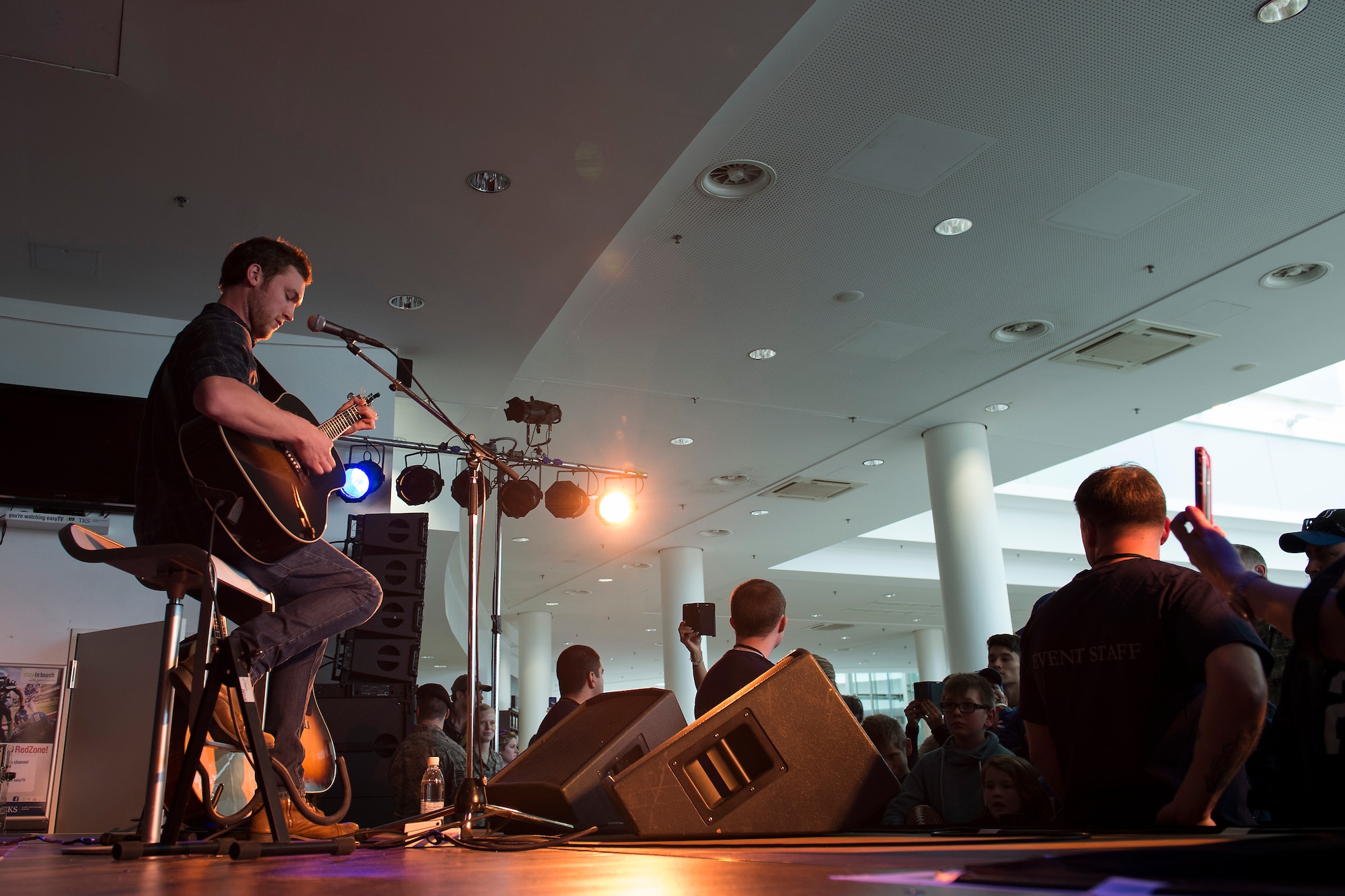 Phillip Phillips, platinum recording artist, sings for military members and their families during the USO Spring Visit at Ramstein Air Base, Germany, March 3, 2015. For their first stop of a multi-country tour, the USO brought Indianapolis Colts players Andrew Luck and Dwayne Allen, Colts coach Chuck Pagano, Pittsburgh Steelers player David DeCastro, entertainers Philip Phillips, Dennis Haysbert, Miss America 2015, Ace Young, Diana DeGarmo, and Jason “Wee Man” Acuna to Ramstein to visit military members and their families. (U.S. Air Force photo/Senior Airman Damon Kasberg) 