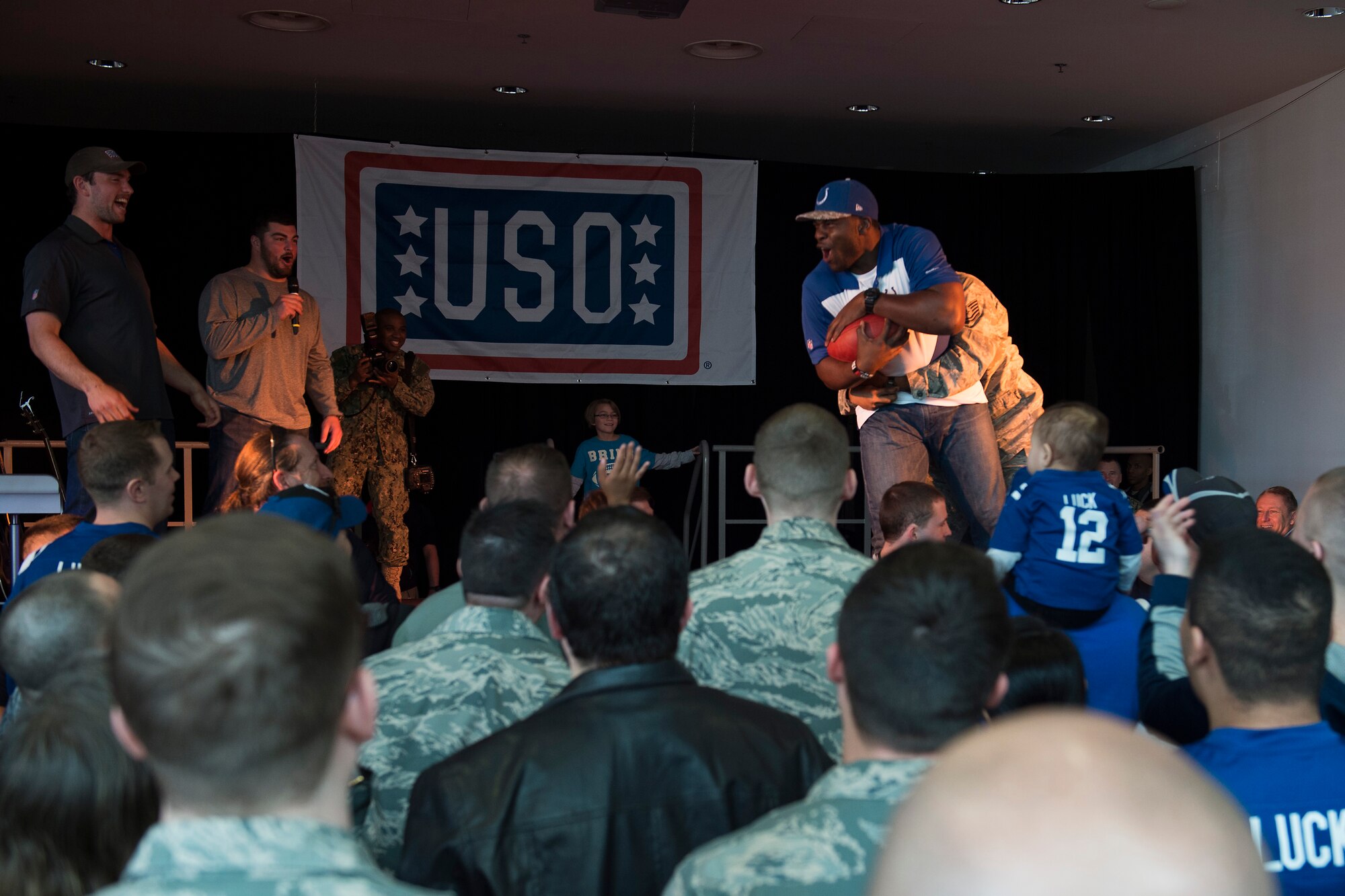 Dwayne Allen, Indianapolis Colts tight end, is tackled by Tech. Sgt. Llewellyn Johnson, Jr., 86th Civil Engineer Squadron Airmen dorm leader, during the USO Spring Visit at Ramstein Air Base, Germany, March 3, 2015. For their first stop of a multi-country tour, the USO brought Indianapolis Colts players Andrew Luck and Dwayne Allen, Colts coach Chuck Pagano, Pittsburgh Steelers player David DeCastro, entertainers Philip Phillips, Dennis Haysbert, Miss America 2015, Ace Young, Diana DeGarmo, and Jason “Wee Man” Acuna to Ramstein to visit military members and their families. (U.S. Air Force photo/Senior Airman Damon Kasberg) 