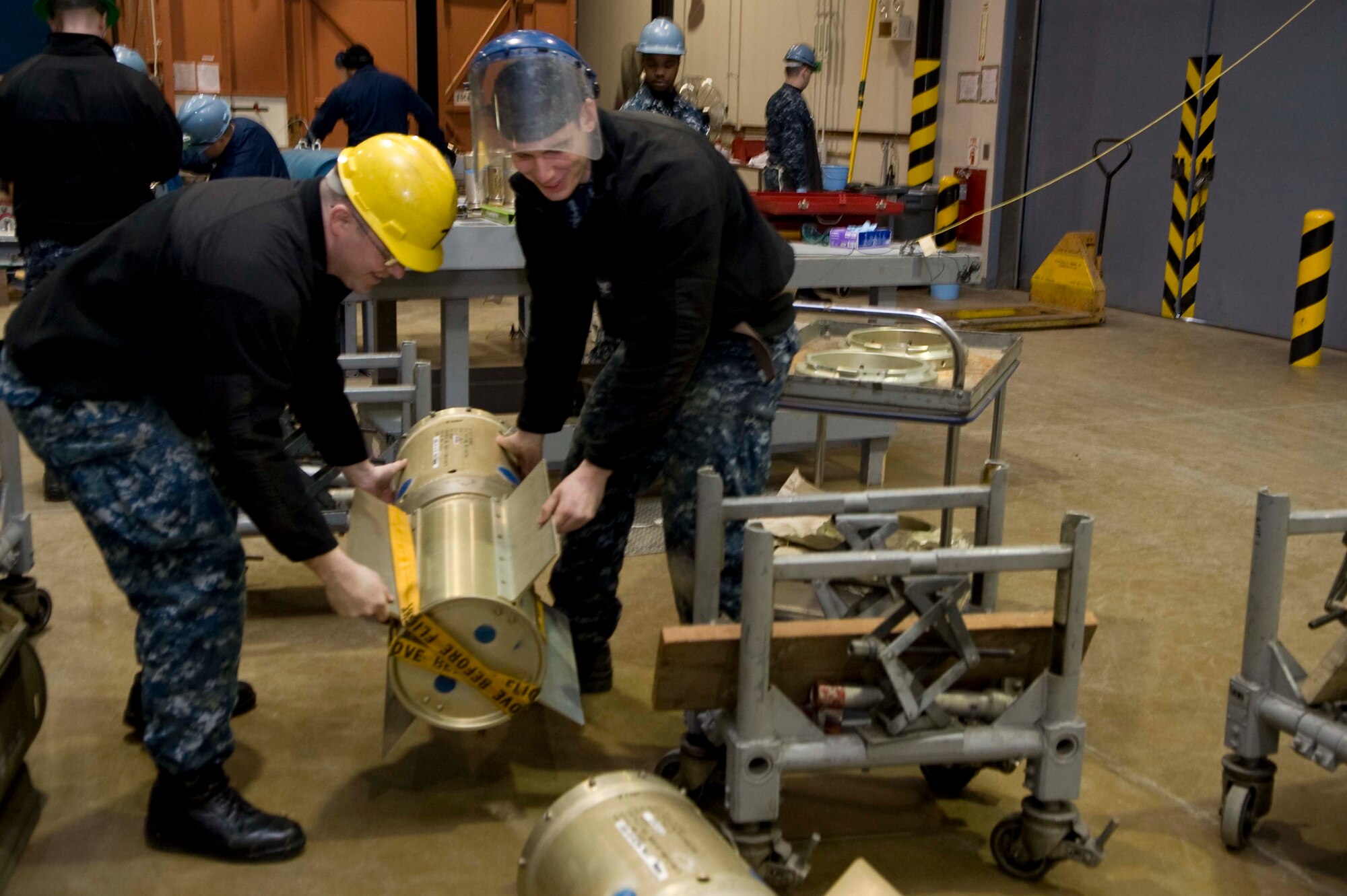 Sailors attached to the Navy Munitions Command East Asia Division Unit Misawa position the tail section of a MK 21 Dolly as part of weapon preparation checks at Misawa Air Base, Japan, March 4, 2015. The NMC team at Misawa assembled 30 underwater mines during training in conjunction with Beverly Sunrise 15-2, an Air Force operational readiness exercise. These training and exercise scenarios help the services ensure they are ready to respond to real-world scenarios.  (U.S. Air Force photo by Staff Sgt. Alyssa C. Wallace/Released)