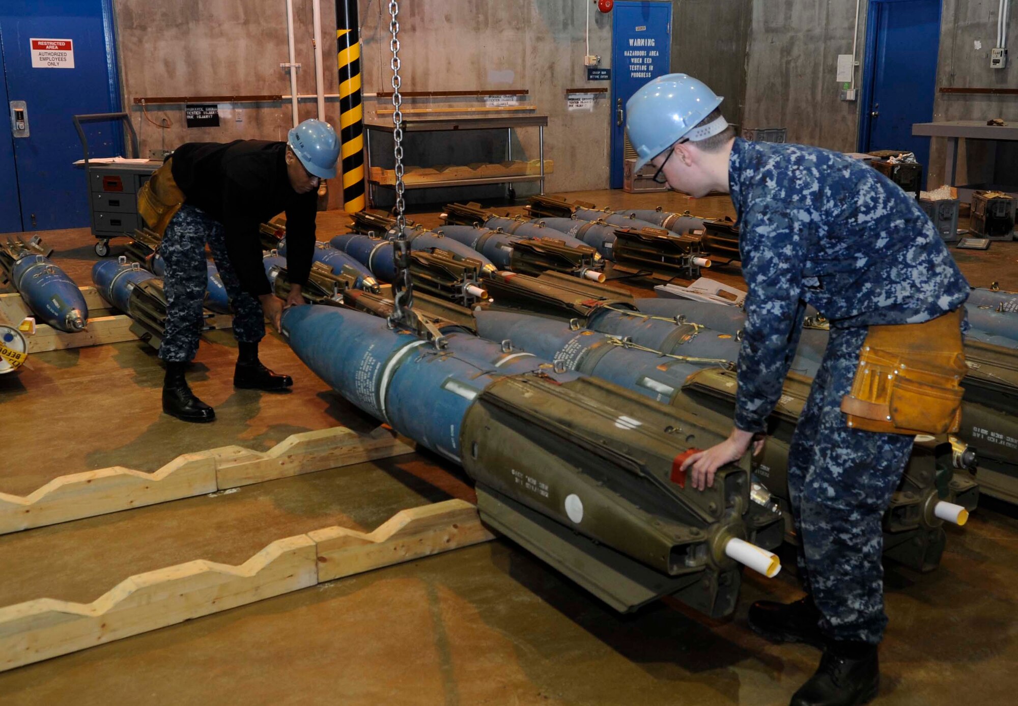 Sailors attached to the Navy Munitions Command East Asia Division Unit Misawa rack a MK 63 underwater mine after configuring the weapon for delivery at Misawa Air Base, Japan, March 4, 2015. Once placed on the stowage racks, an inspection is performed to determine the weapon’s reliability. Sailors at Misawa performed a weapons training exercise in conjunction with an Air Force operational readiness exercise that challenged both services on their joint operability. The underwater mines are deployed by Navy P-3 Orion aircraft. (U.S. Air Force photo by Airman 1st Class Jordyn Rucker/Released)