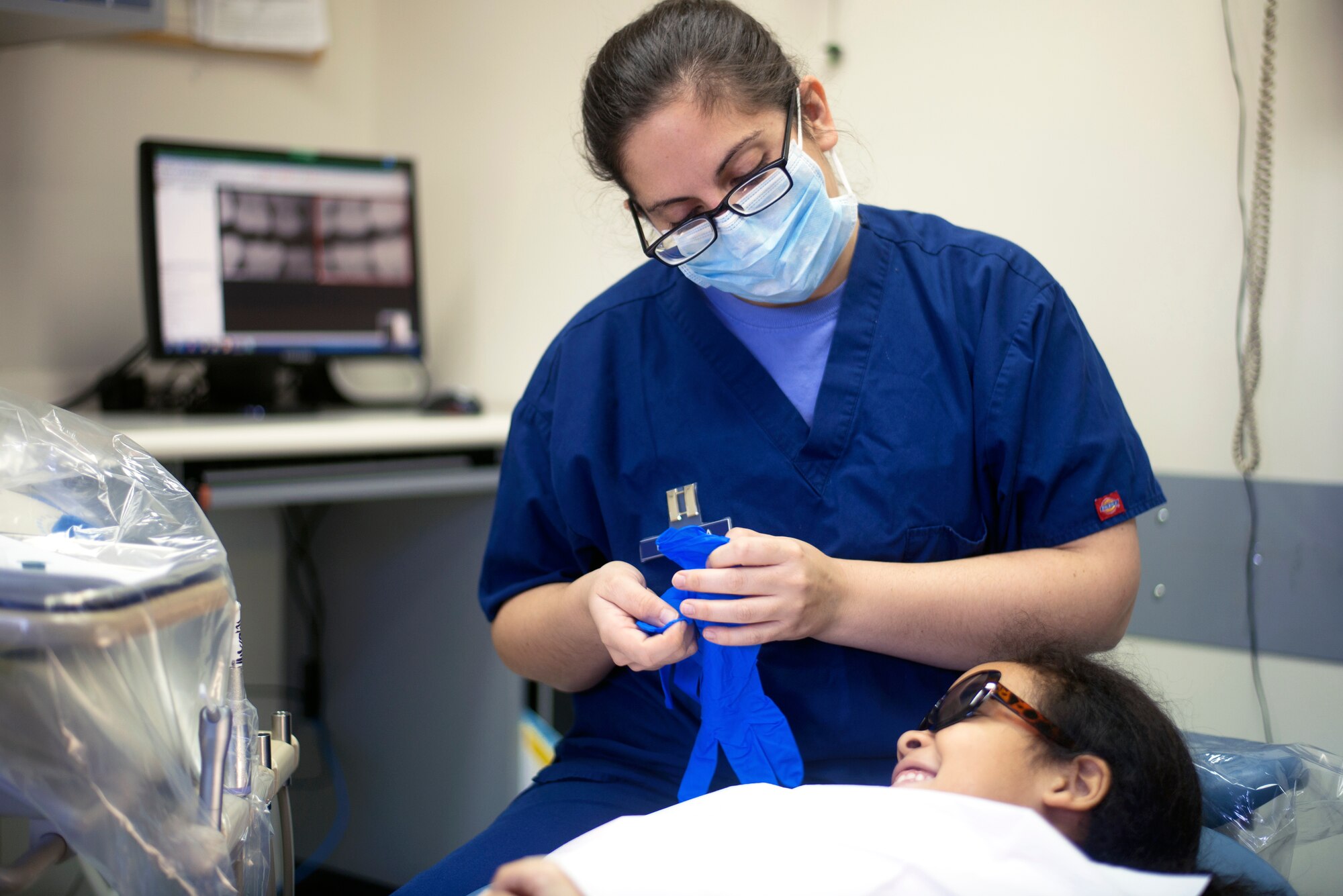 Capt. Erin McNamara, 374th Dental Squadron general dentist, prepares to examine the teeth of Paige Lukes, patient at the Yokota Dental Clinic, Feb. 28, 2015, during the Little Teeth-Big Smiles event. McNamara was one of many 374th DS members to participate and offer preventative oral care to children at the LTBS event. (U.S. Air Force photo by Airman 1st Class Delano Scott/Released)