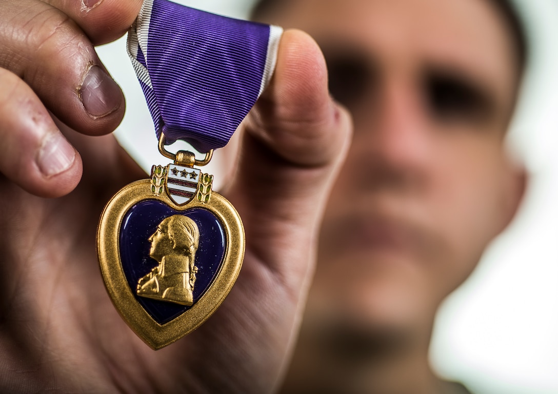 An airman holds up his Purple Heart medal.