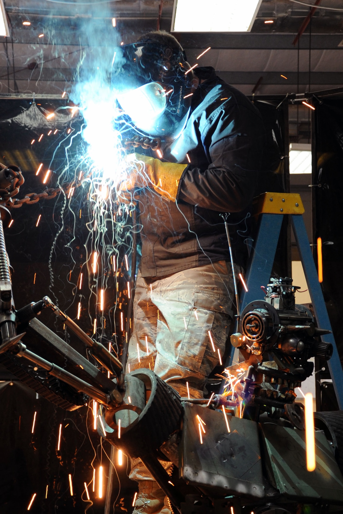 Tech. Sgt. Patrick Pittman, 386th Expeditionary Maintenance Squadron Combat Metals Flight machinist, puts the finishing welds on his scrap metal sculpture. Dubbed "Ironman" by it's creators, the project utilized more than 200 pieces of scrap metal collected by a volunteer crew of four, and it took two weeks to assemble. (U.S. Air Force photo by Master Sgt. Eric Petosky)