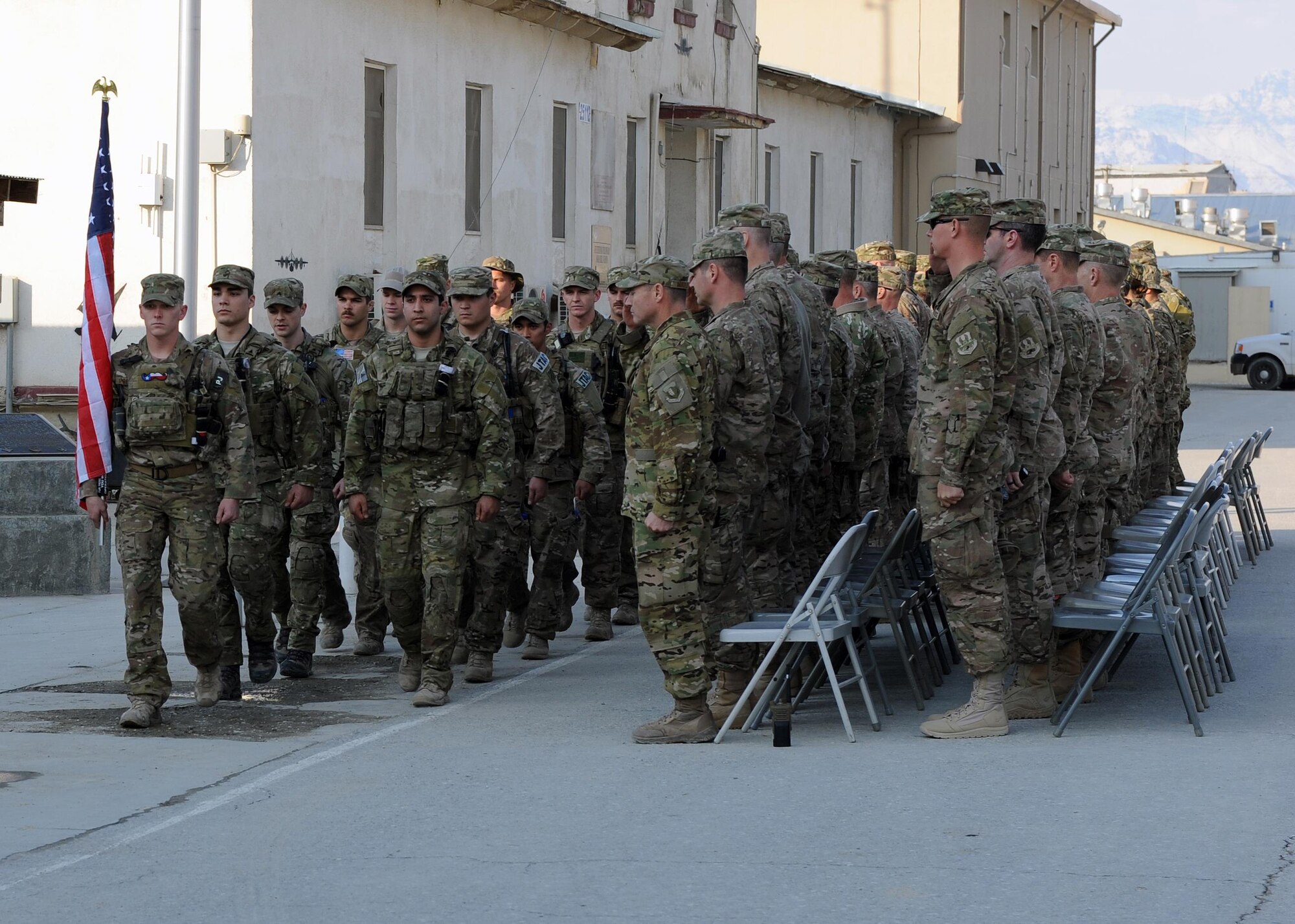 U.S. servicemembers render a salute as a formation of multiservice special operators march with a U.S. flag bearing the names of seven special operators who were killed March 4, 2002 during Operation Anaconda: U.S. Air Force Senior Airman Jason Cunningham, U.S. Army Cpl. Matthew Commons, U.S. Army Spc. Marc Anderson, U.S. Army Sgt. Phillip Svitak, U.S. Army Sgt. Bradley Crose, U.S. Navy Petty Officer 1st Class Neil Roberts and U.S. Air Force Tech. Sgt. John Chapman, March 3, 2015 at Bagram Airfield, Afghanistan. Servicemembers from all branches conducted a 24-hour vigil run and a retreat ceremony to honor the 13th anniversary of their deaths and pay homage to a legacy of heroism. (U.S. Air Force photo by Staff Sgt. Whitney Amstutz/released)