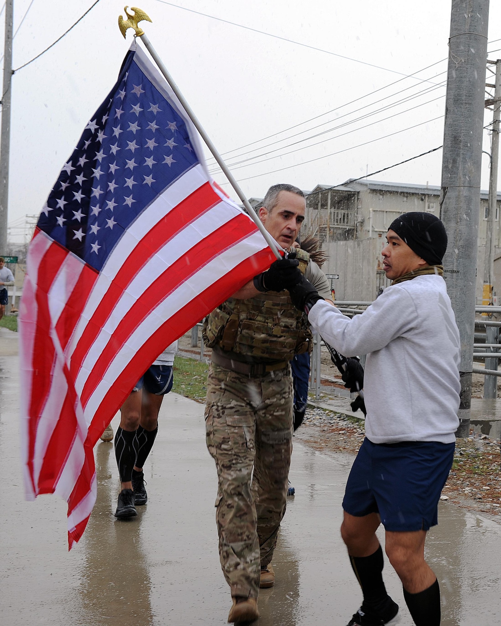 U.S. Air Force Chief Master Sgt. Ramon "CZ" Colon-Lopez, Air Force Central Command command chief, passes a U.S. flag bearing the names of seven special operators who were killed March 4, 2002 during Operation Anaconda: U.S. Air Force Senior Airman Jason Cunningham, U.S. Army Cpl. Matthew Commons, U.S. Army Spc. Marc Anderson, U.S. Army Sgt. Phillip Svitak, U.S. Army Sgt. Bradley Crose, U.S. Navy Petty Officer 1st Class Neil Roberts and U.S. Air Force Tech. Sgt. John Chapman, March 4, 2015 at Bagram Airfield, Afghanistan. Servicemembers from all branches conducted a 24-hour vigil run and a retreat ceremony to honor the 13th anniversary of their deaths and pay homage to a legacy of heroism. (U.S. Air Force photo by Staff Sgt. Whitney Amstutz/released)