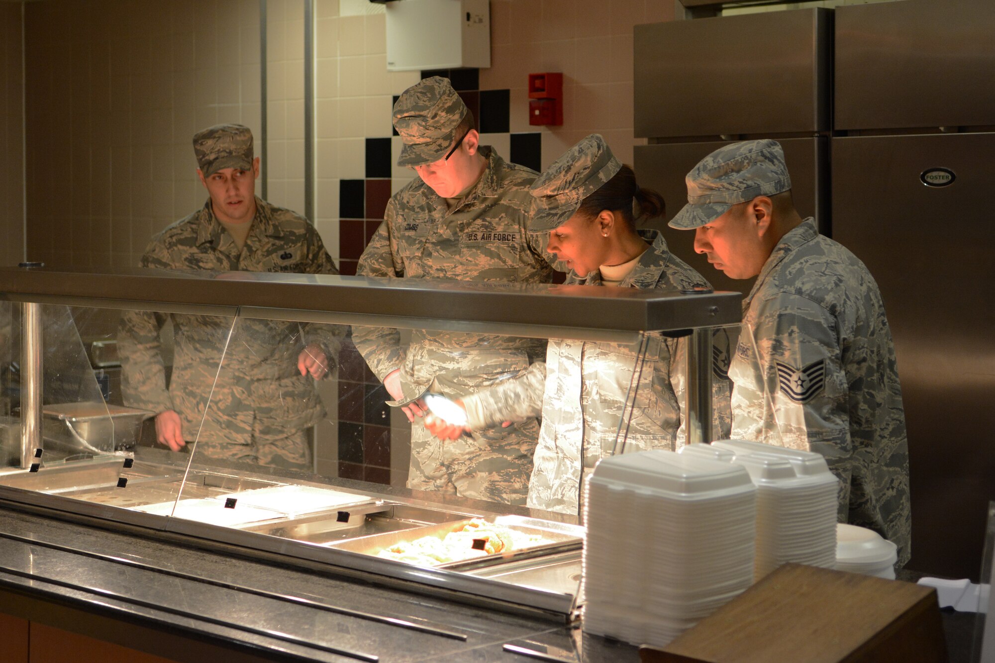 Tech. Sgt. Andrew Combs, 115th Force Support Squadron, brainstorms with the active-duty Airmen from Mildenhall Air Force Base, England, in the Mildenhall dining facility Feb. 19, 2015. The boilers went out on the serving line, so they were forced to develop a plan to keep the food warm. The 115 FW Airmen integrated themselves and trained alongside active-duty forces overseas for two weeks. (U.S. Air National Guard photo by Senior Airman Andrea F. Rhode)