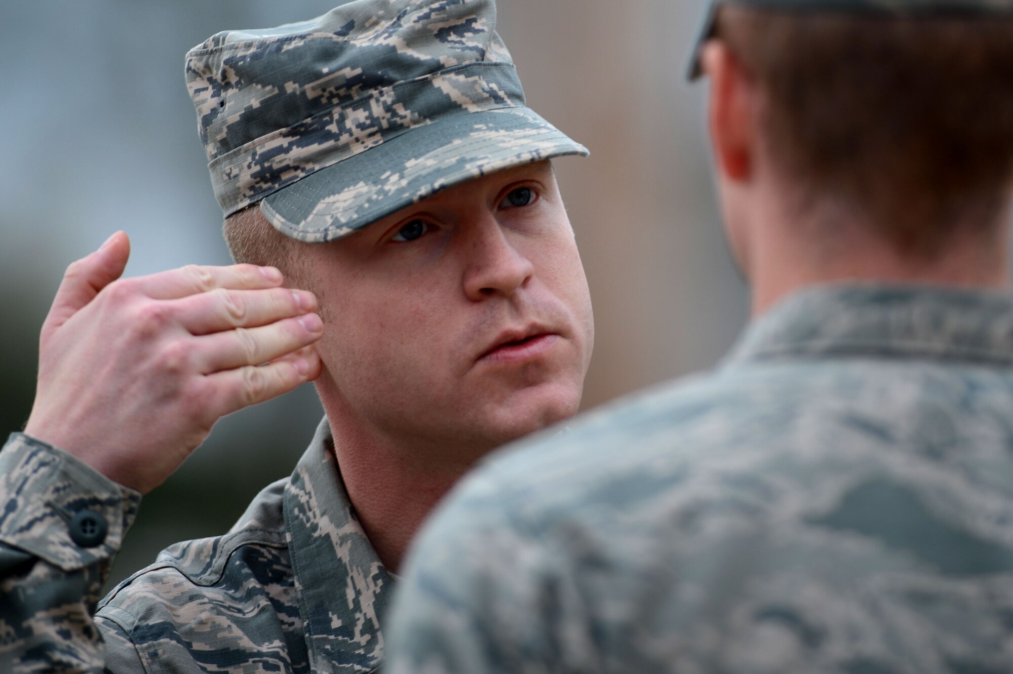 U.S. Air Force Staff Sgt. Caleb Hall, 20th Force Support Squadron Senior Master Sgt. David B. Reed Airman Leadership School instructor, explains to a student how to wear the Airman Battle Uniform cover during a uniform inspection at Shaw Air Force Base, S.C., March 5, 2015. While in ALS, Airmen learn supervisory communication skills, professional Airmen knowledge, expeditionary Airmen tactics, and supervision of Airmen skills. (U.S. Air force photo by Senior Airman Jensen Stidham/Released)