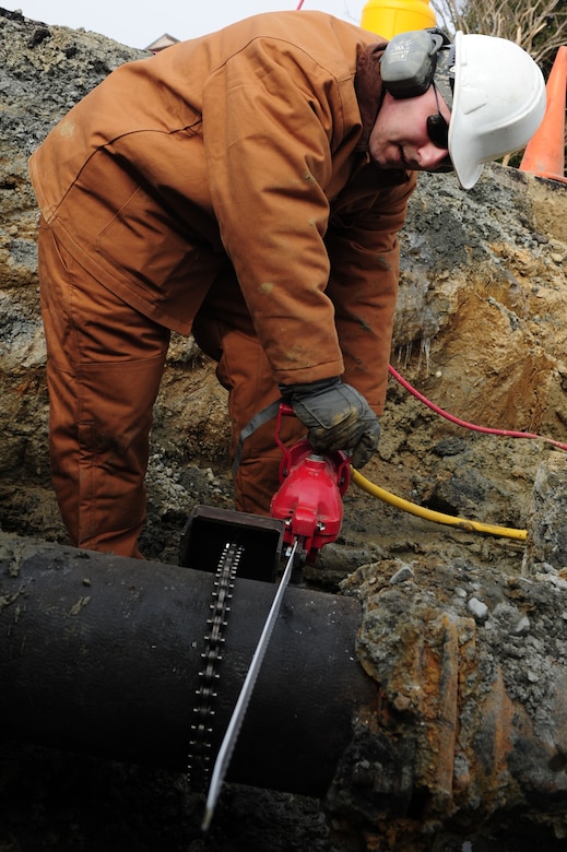 U.S. Air Force Senior Airman Anthony Boe, 633rd Civil Engineer Squadron water and fuel systems apprentice, saws into a water pipe near the King Street gate at Langley Air Force Base, Va., Feb. 24, 2015. The water pipe and a water line ruptured during inclement weather, causing the gate to close. Through the work of CES Airmen, the gate reopened March 2, 2015. (U.S. Air Force photo by Staff Sgt. Natasha Stannard/Released)