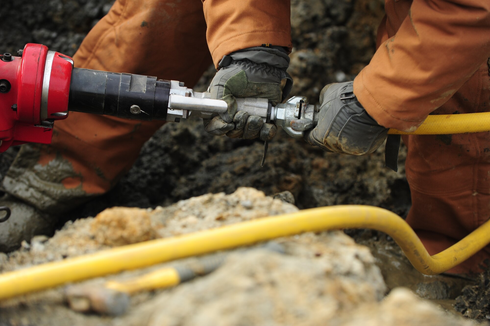 U.S. Air Force Senior Airman Anthony Boe, 633rd Civil Engineer Squadron water and fuel systems apprentice, connects a high pressure air-line to a saw used to cut a ductile iron water pipeline near the King Street gate at Langley Air Force Base, Va., Feb. 24, 2015. The CES water and fuels systems shop is responsible for maintaining and repairing all system lines, water heaters, sinks, and emergency gas breaks on base as well as maintaining water treatment facilities. (U.S. Air Force photo by Staff Sgt. Natasha Stannard/Released)