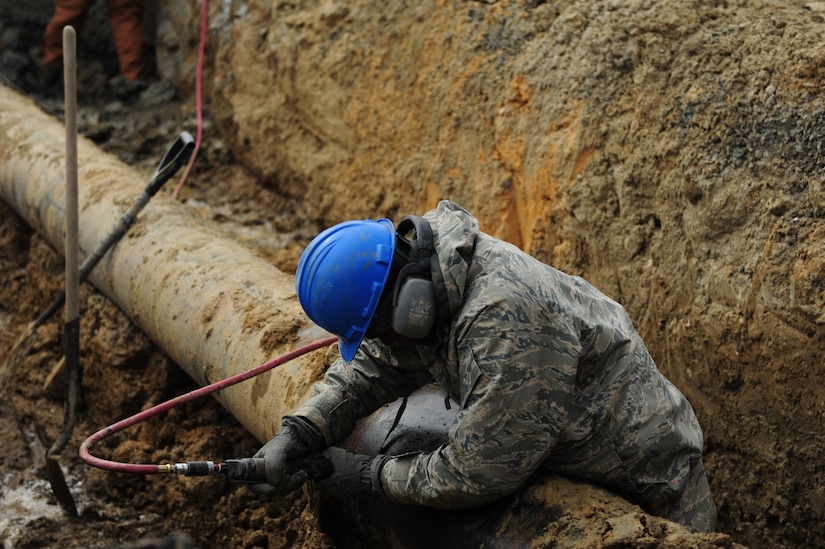 U.S. Air Force Airman 1st Class Patrick Marvel, 633rd Civil Engineer Squadron water and fuel systems journeyman, prepares to cut, remove and replace a waterline near the King Street gate at Langley Air Force Base, Va., Feb. 24, 2015. The CES team dug to the line using heavy equipment, so they reach the damaged portion of the line and replace it. (U.S. Air Force photo by Staff Sgt. Natasha Stannard/Released)