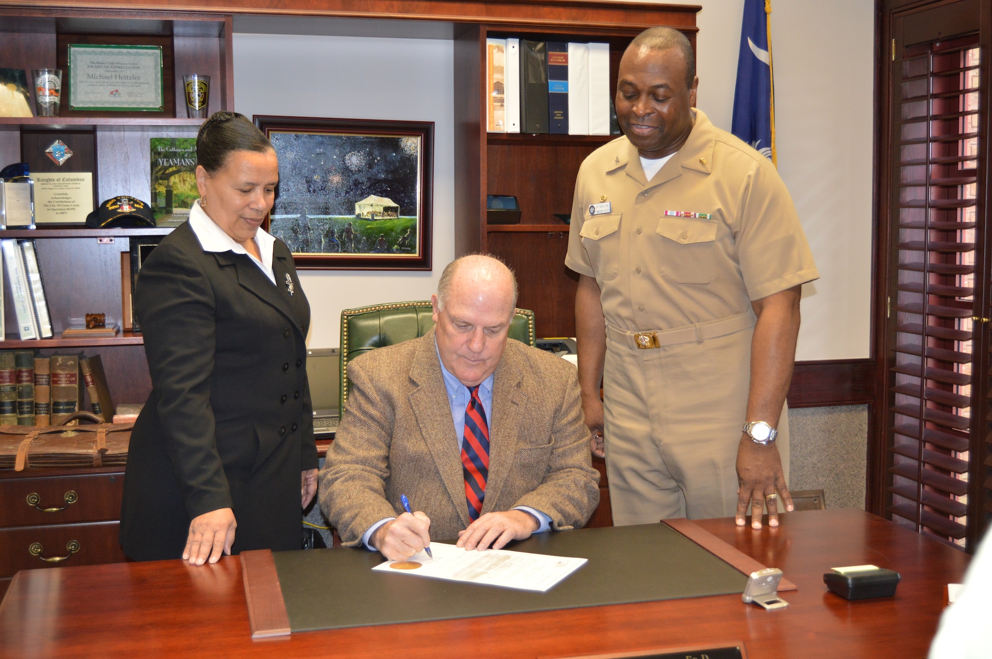 Goose Creek Mayor Michael Heitzler, center, with Capt. Marvin Jones, Naval Health Clinic
Charleston commanding officer, right, and Ruth Warren-Goldston, NHCC Patient Safety officer, signs a proclamation March 2, 2015 designating March 8 to 14 Patient Safety Awareness Week in his office at Goose Creek City Hall. Patient Safety Awareness Week is an annual education and awareness campaign for healthcare safety led by the National Patient Safety Foundation. Each year, NHCC joins healthcare organizations from around the globe to participate in educational events that empower hospital staff and patients to eliminate preventable patient harm and provide the highest quality of care for patients. (Navy photo/Kris Patterson)
