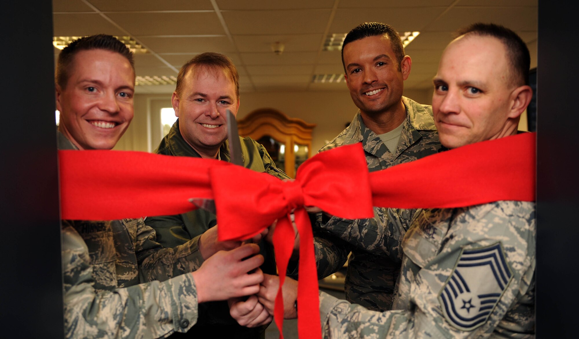 (From left to right) U.S. Air Force Tech. Sgt. Kalob Hinners, a Pitsenbarger Airman Leadership School instructor, U.S. Air Force Col. Lars Hubert, 52nd Fighter Wing vice commander, U.S. Air Force Master Sgt. Roberto Oregon, Pitsenbarger Airman Leadership School commandant, and U.S. Air Force Chief Master Sgt. Thomas Cooper, 52nd Mission Support Group superintendent, pose for a ceremonial ribbon-cutting during the Pitsenbarger Heritage Room ribbon-cutting ceremony in the Pitsenbarger Airman Leadership School at Spangdahlem Air Base, Germany, March 4, 2015. Hinners designed the heritage room over a two-year period before its opening that day. (U.S. Air Force photo by Airman 1st Class Timothy Kim/Released)