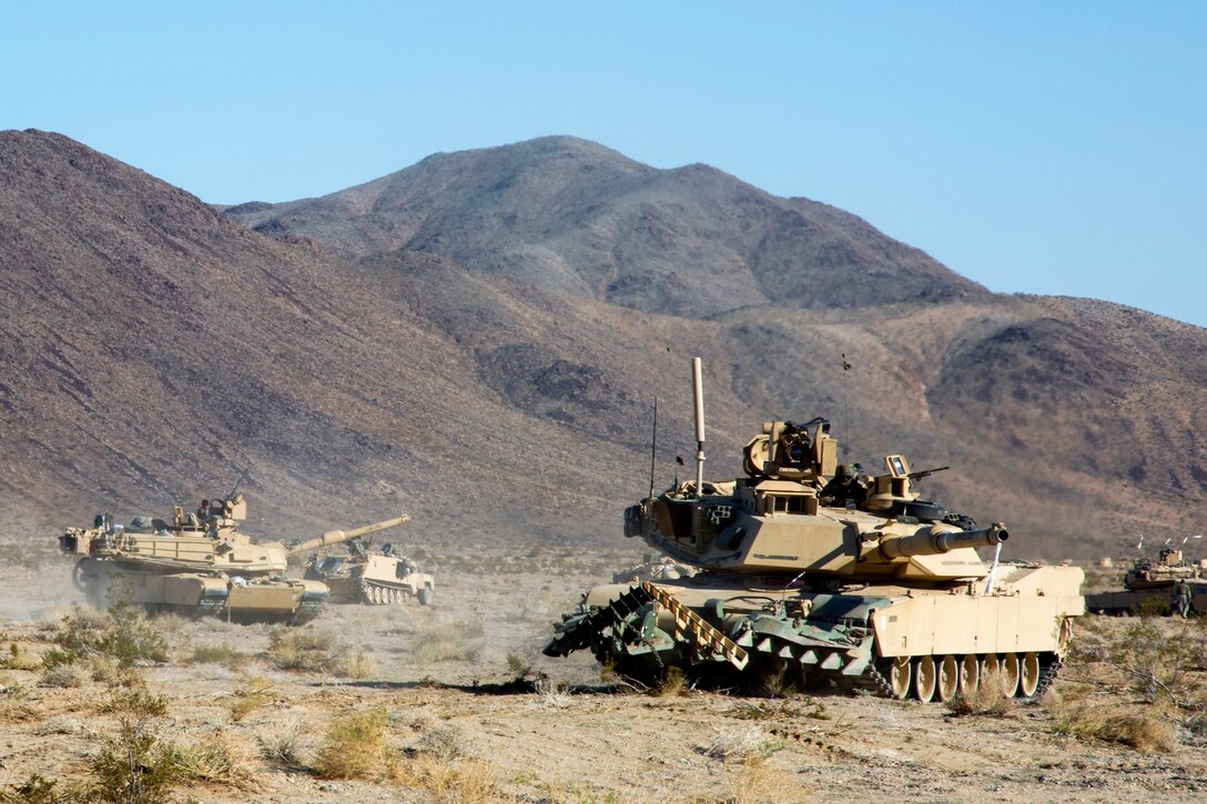 Soldiers manning M1A1 Abrams tanks assault a simulated enemy compound ...