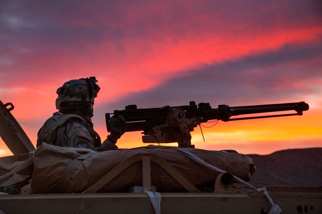A soldier mans a machine gun from the turret of a tactical vehicle while providing security outside a simulated enemy compound during Decisive Action Rotation 15-05 at the National Training Center on Fort Irwin, Calif., Feb. 25, 2015.