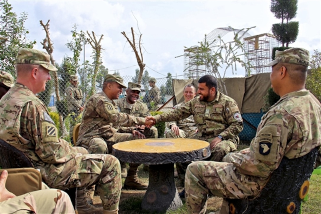 Afghan Brig. Gen. Mohammad Nasir Safie, right, the commander of the National Civil Order Police's 2nd Brigade, shakes hands with U.S. Army Col. Gregory Stokes, commander of the Police Advisory Team assigned to Train, Advise and Assist Command East, as other U.S. military leaders look on during a visit in Nangarhar province, Afghanistan, March 3, 2015.