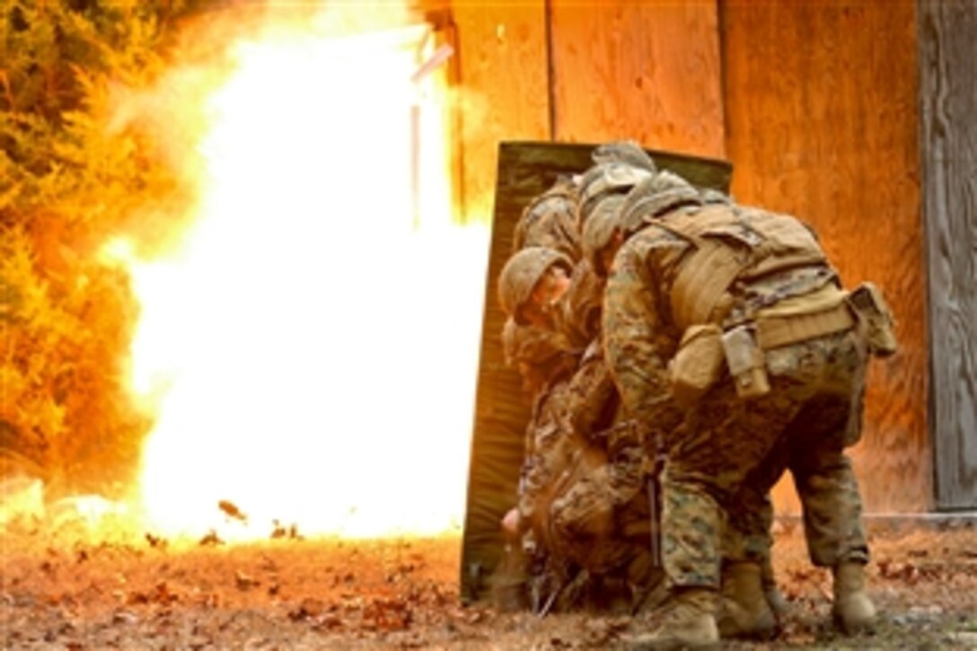 Marines take cover behind a blast blanket as a detonation cord ignites, blowing a door in and giving the Marines a clear passage to breach a building during an urban breaching course on Camp Lejeune, N.C., March 3, 2015. The Marines are assigned to the 2nd Marine Division's Mobility Assault Company, 2nd Combat Engineer Battalion.