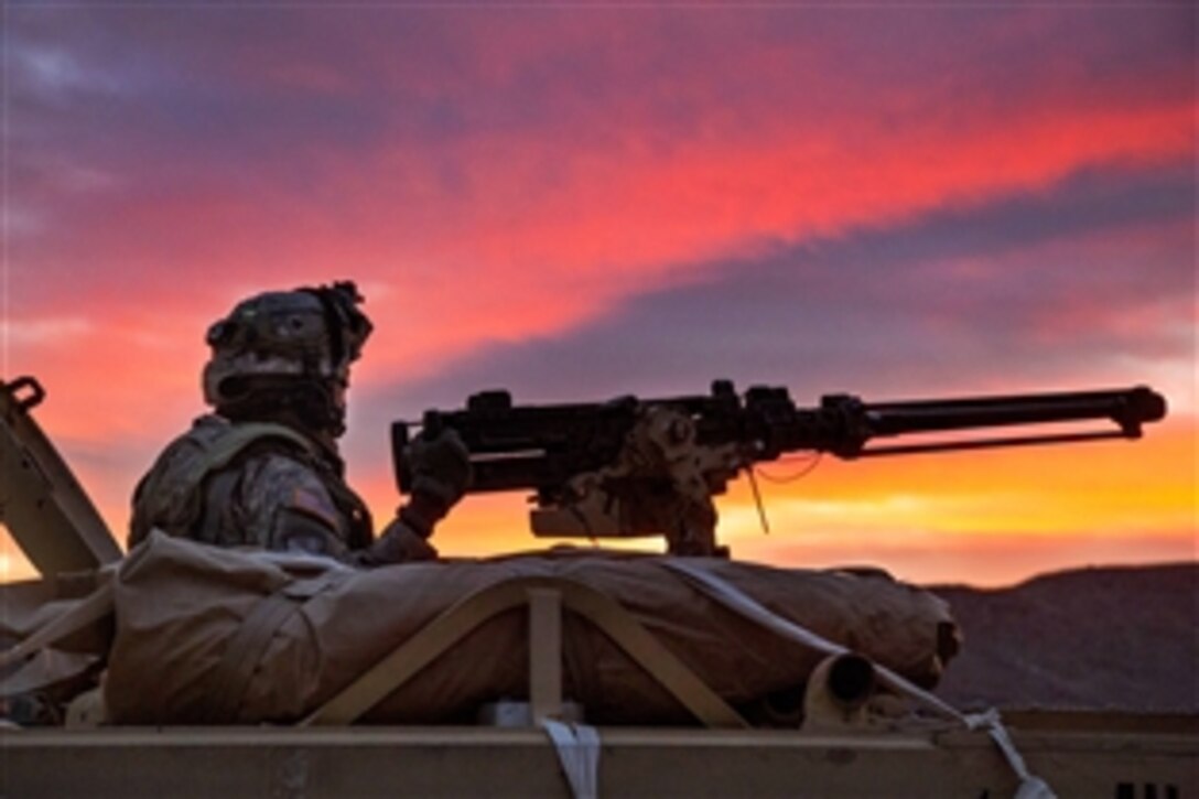 A soldier mans a machine gun from a tactical vehicle's turret while providing security outside a simulated enemy compound during Decisive Action Rotation 15-05 at the National Training Center on Fort Irwin, Calif., Feb. 25, 2015.  The rotation ensures brigades remain versatile, responsive and consistently available for the present and unforeseen future contingencies.