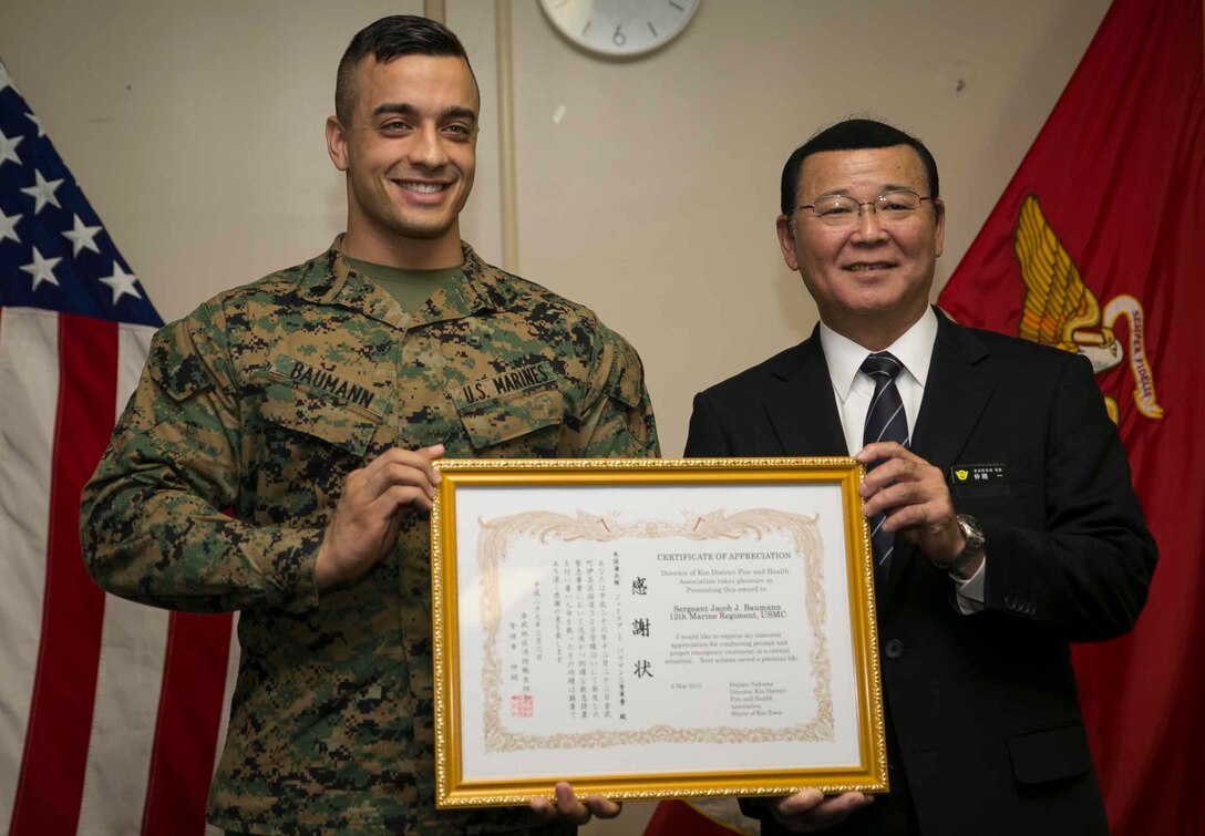 U.S. Marine Sgt. Jacob J. Baumann, left, and Hajime Nakama, the Mayor of Kin Town, pose for a photo with an award Sgt. Baumann received March 6 on Camp Hansen. Baumann, from Junction City, Kansas, was awarded for helping save the life an elderly Okinawan Gentlemen Dec. 23. Baumann was driving his car near Camp Hansen, where he is stationed, when he saw someone riding a bike fall and not get up. Because of Baumann’s military training, he realized the man’s heartbeat was irregular so he began CPR. He resuscitated the man before the paramedics arrived to take over for Baumann. Because of his actions, Baumann received an award from Kin Town’s fire and emergency services as well as the Navy and Marine Corps achievement medal. “I would like to thank (Sgt. Baumann) for his quick actions that helped to save a life,” said Nakama. “I think that he is a positive role model for his fellow Marines.” Baumann is a fire support man with Headquarters Battery, 12th Marine Regiment, 3rd Marine Division, III Marine Expeditionary Force. 