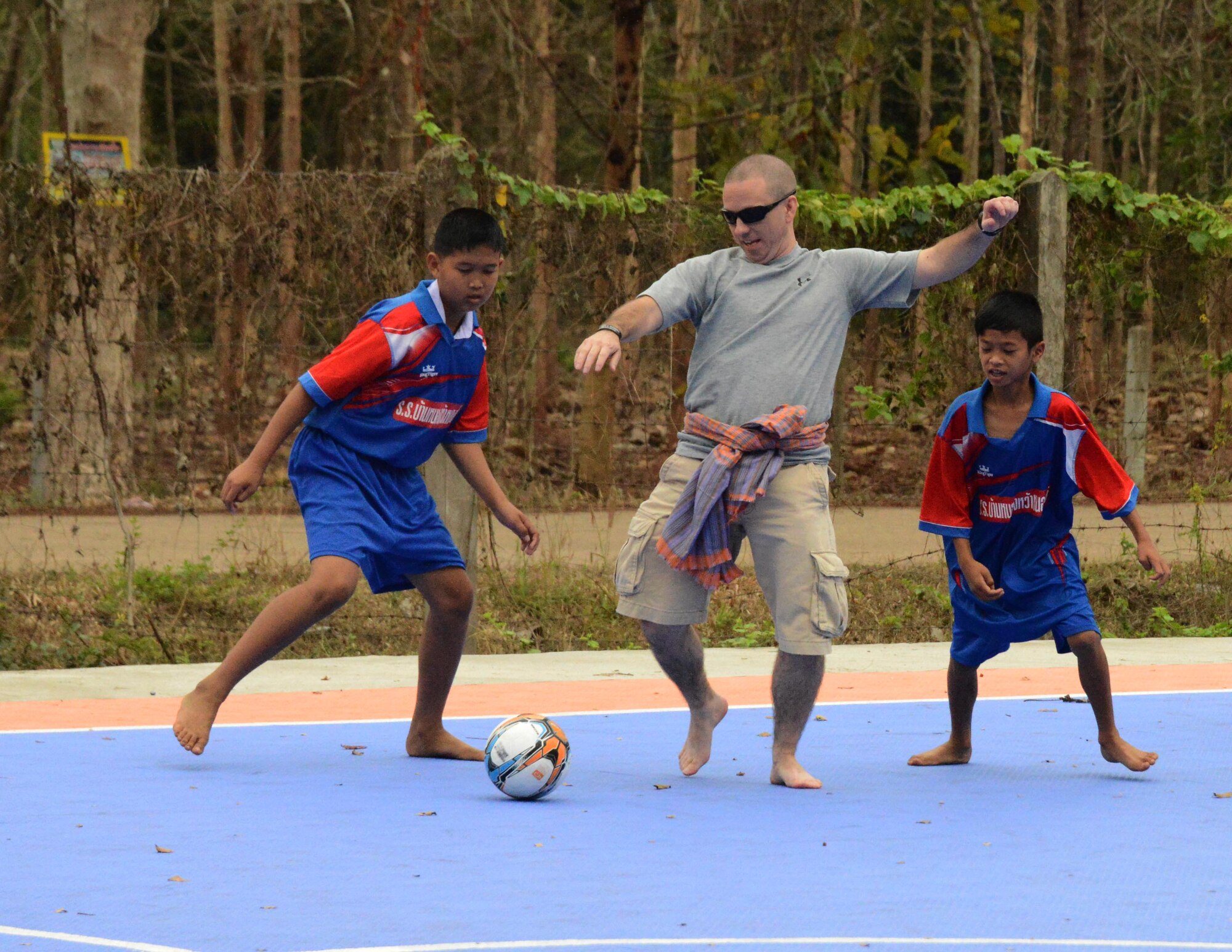 Senior Master Sgt. Jeremy Johnson, 353rd Special Operations Maintenance Squadron, plays soccer with children from Baan Nong Pahi School in Udon Thani, Thailand,  during a visit Feb. 18, 2015.  Members from the 353rd Special Operations Group raised more than $1,000 to donate sports equipment, ice cream, water coolers and medical supplies.  (U.S. Air Force photo by Tech. Sgt. Kristine Dreyer)