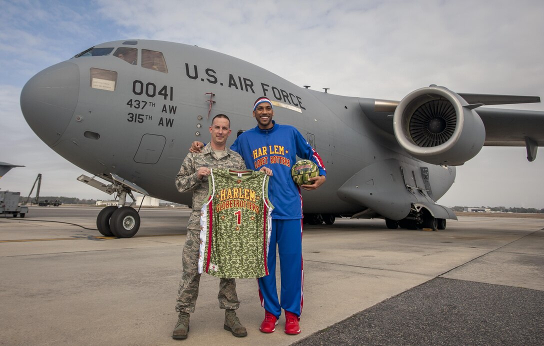 Tech. Sgt. Jeffrey Landis, 315th Maintenance Squadron, Hold up his new Harlem Globetrotter jersey with Globetrotter "Zeus" McClurkin outside a C-17 Globemaster III earlier this week. Landis was selected as the Globetrotters' Hometown Hero for their March 10 game in North Charleston. (U.S. Air Force Photo by Senior Airman Thomas Brading)
